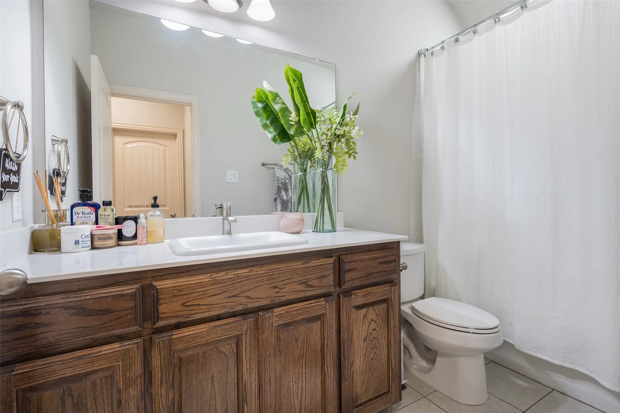 Vanity with wood-finish cabinetry, white countertop, integrated rectangular sink, and chrome faucet