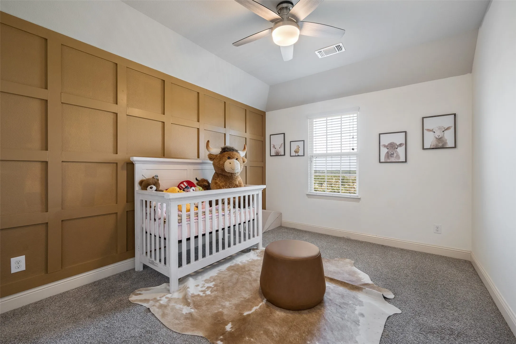 Accent wall with grid paneling, vaulted ceiling, ceiling fan with integrated lighting, carpeted flooring, and a single window with blinds