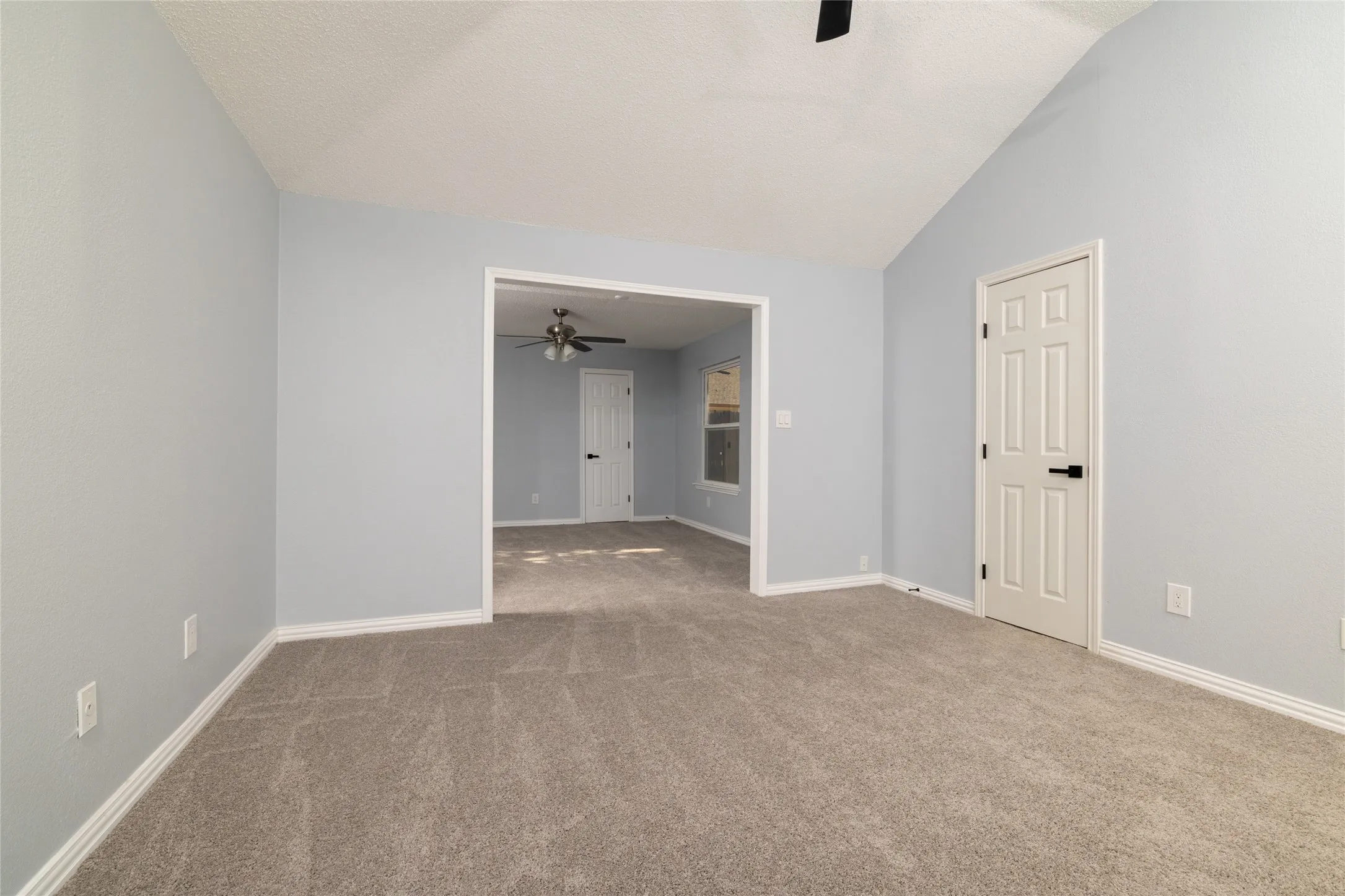 Spacious primary living area featuring neutral carpeting, fresh white walls, and abundant natural light