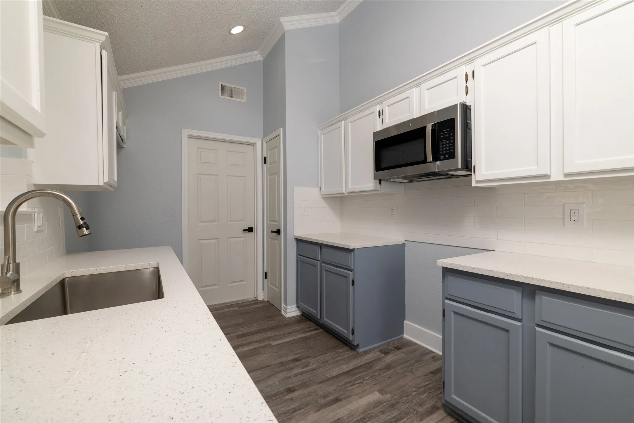 Kitchen featuring vaulted ceilings, wood-finish flooring, white subway tile backsplash, white countertops, and stainless steel appliances