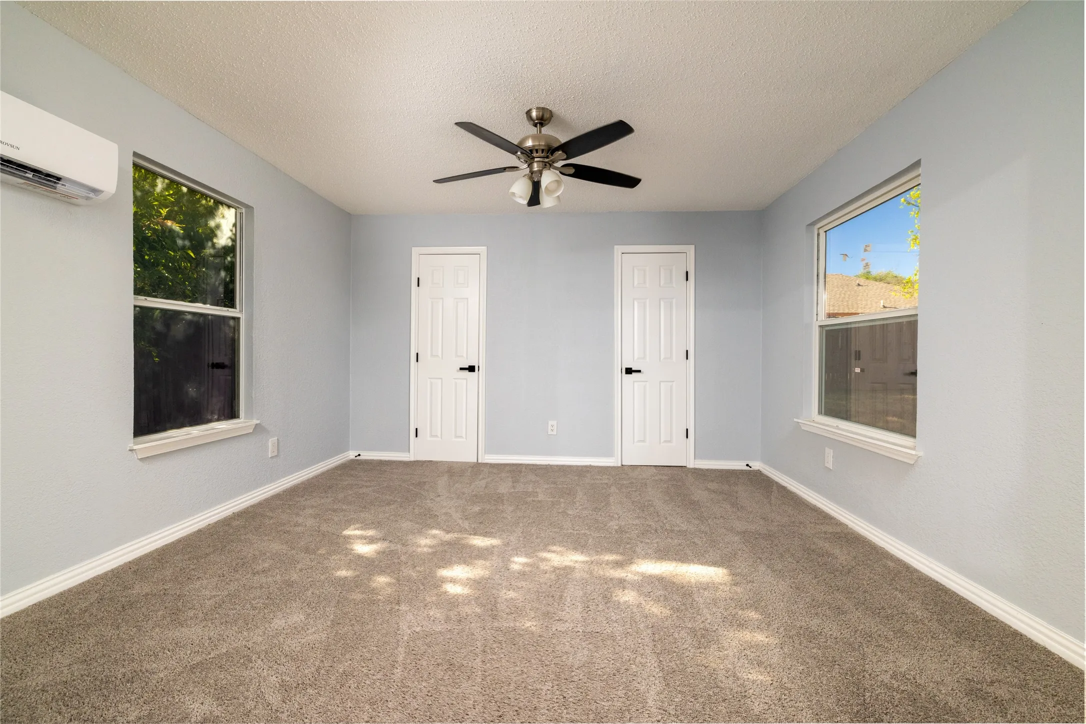 Bonus room serves also as a 4th bedroom with neutral wall paint, two windows, two paneled doors with black hardware, ceiling fan with light kit, and carpet flooring