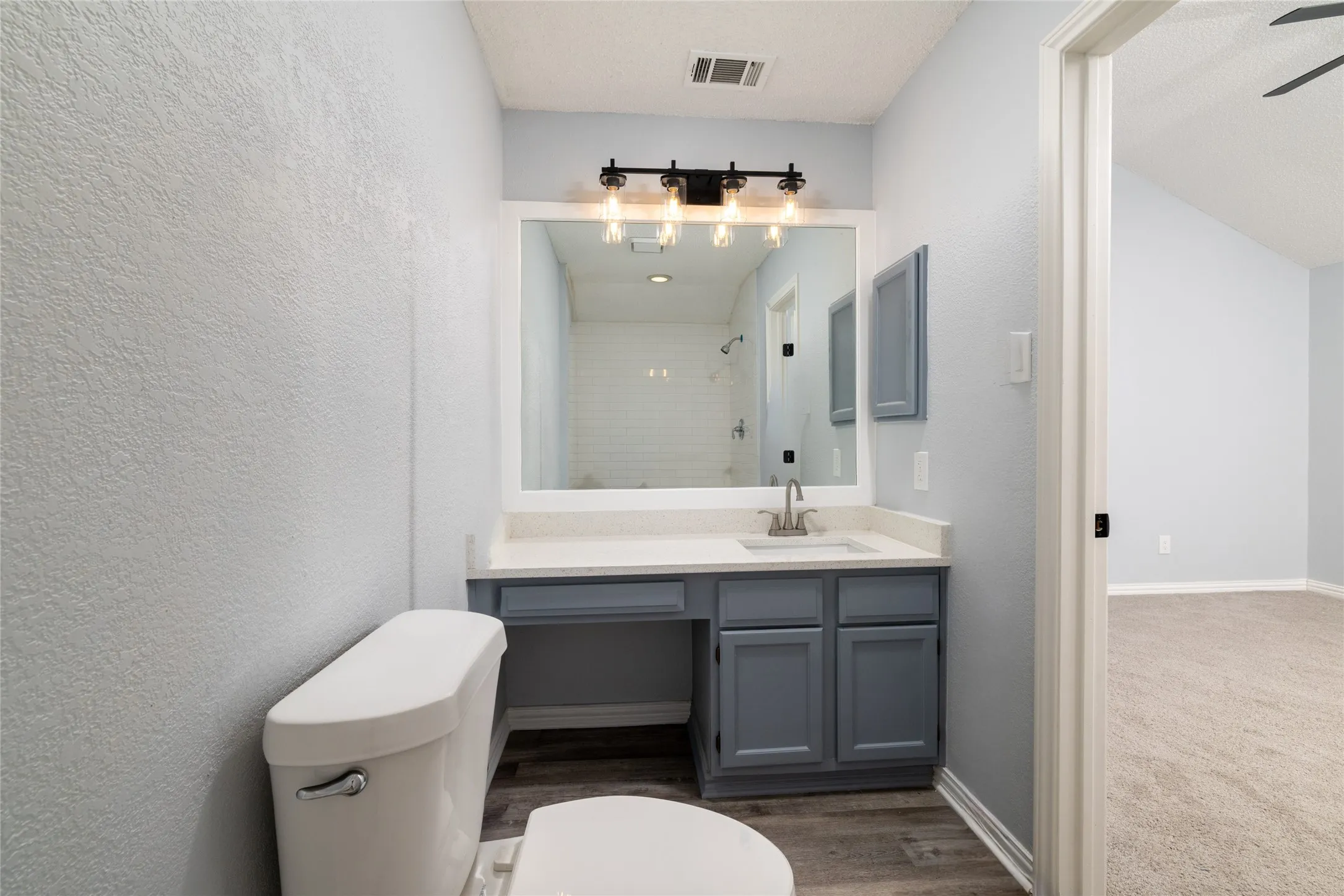 Vanity with integrated sink, wood-like LVP  flooring, built-in cabinetry, and a framed mirror