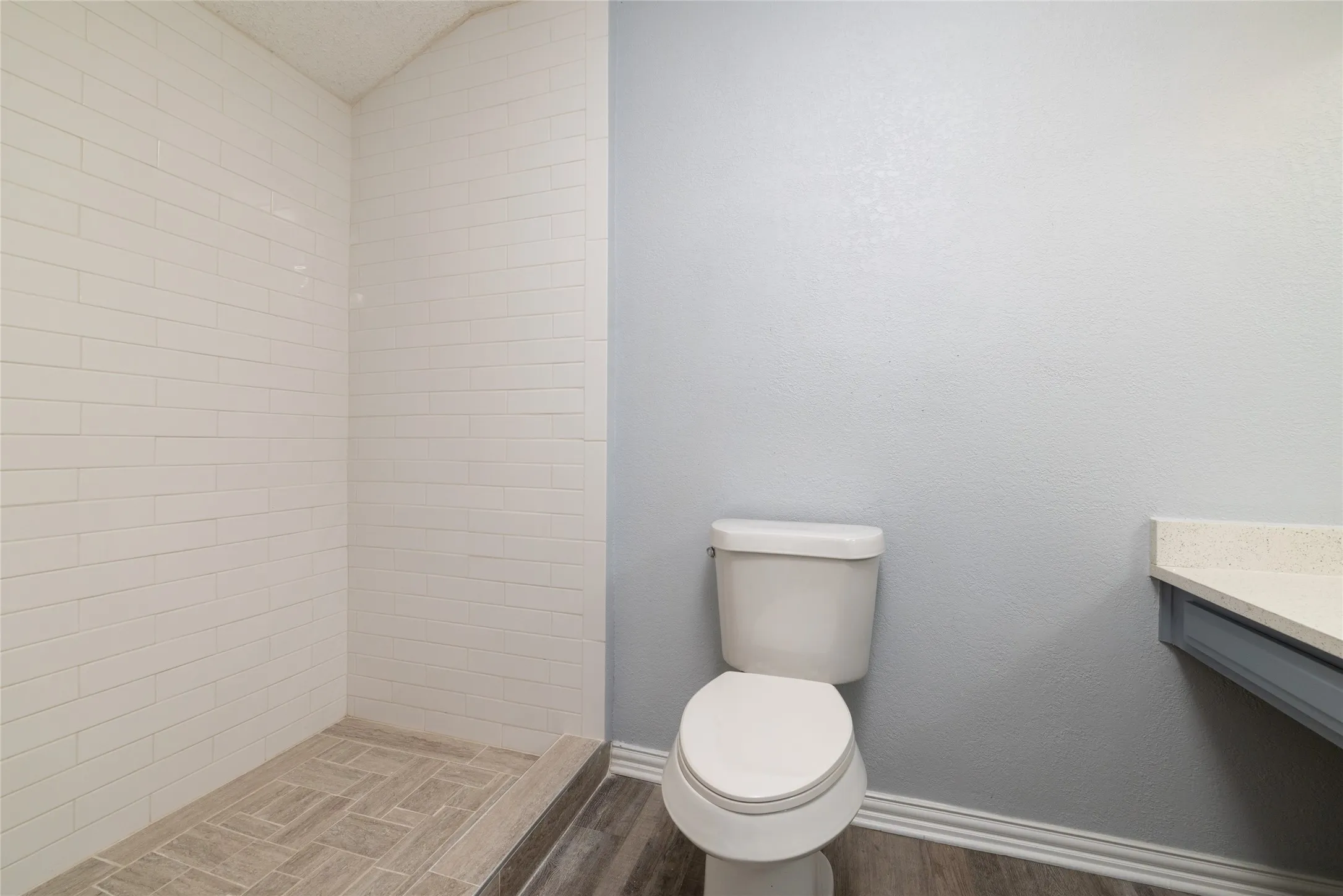 Walk-in shower with horizontal white subway tile and herringbone-patterned floor