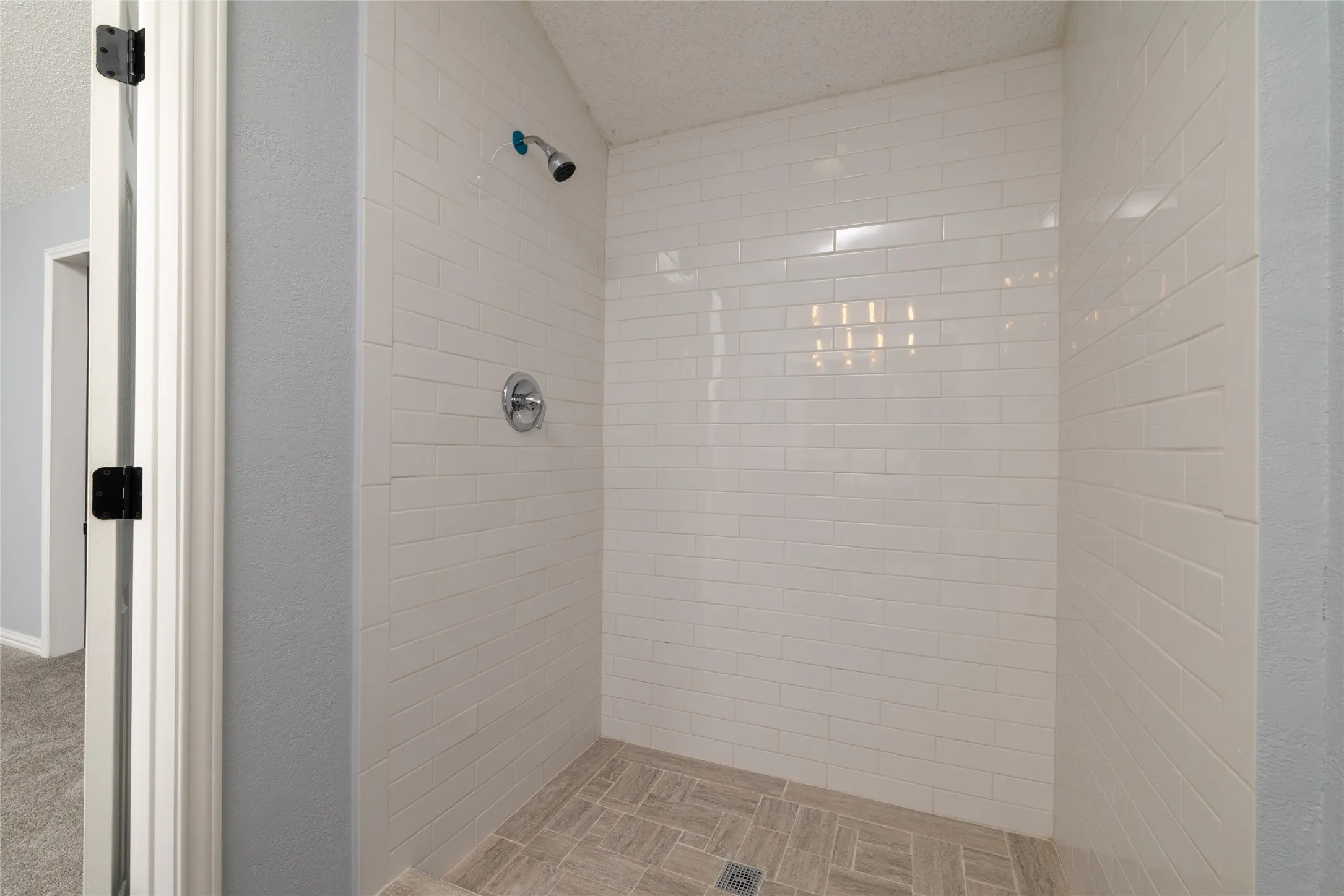 Walk-in shower with subway tile surround, tiled flooring, and chrome fixtures