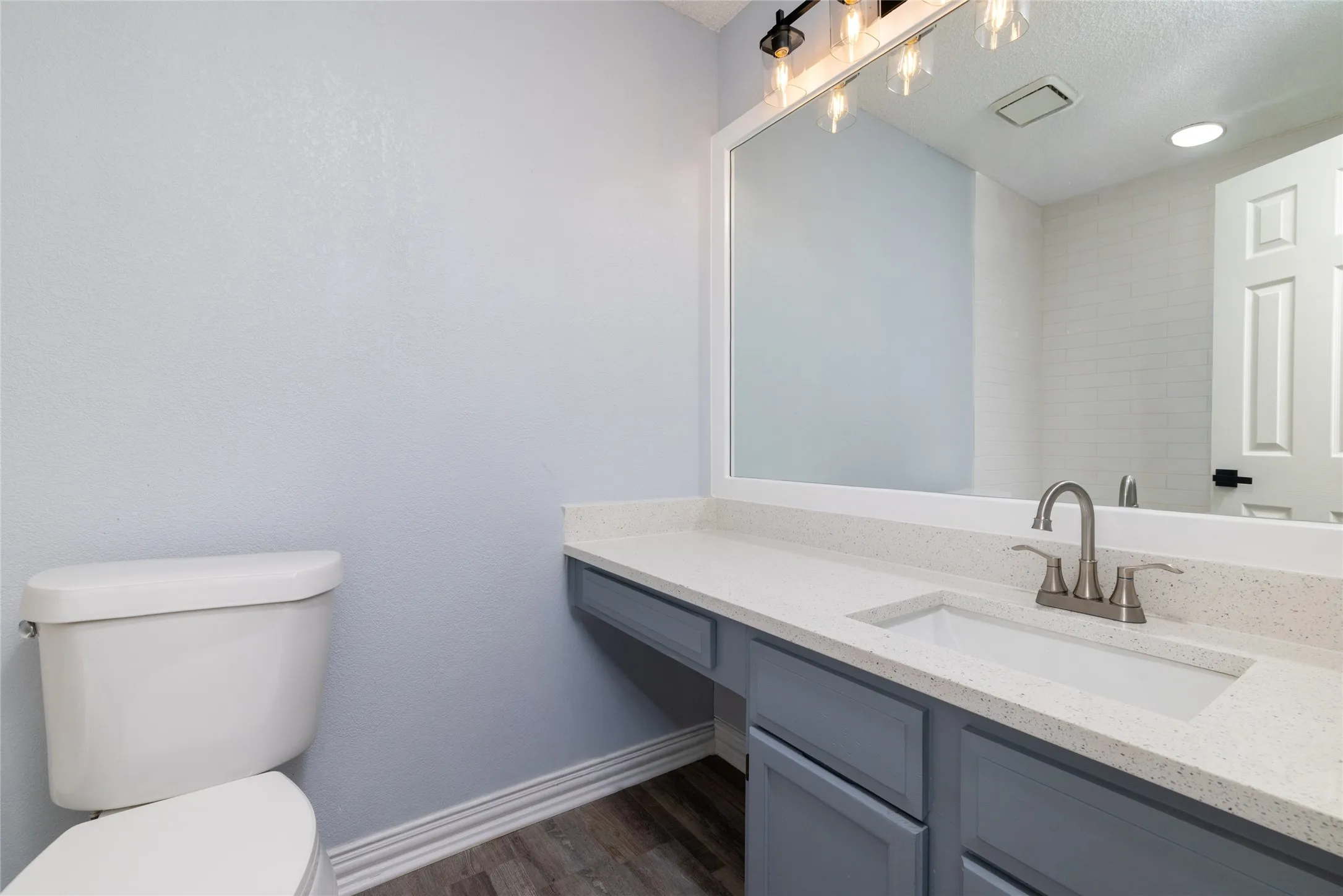 Modern vanity with a light gray cabinet, white countertop, integrated sink, and brushed nickel faucet