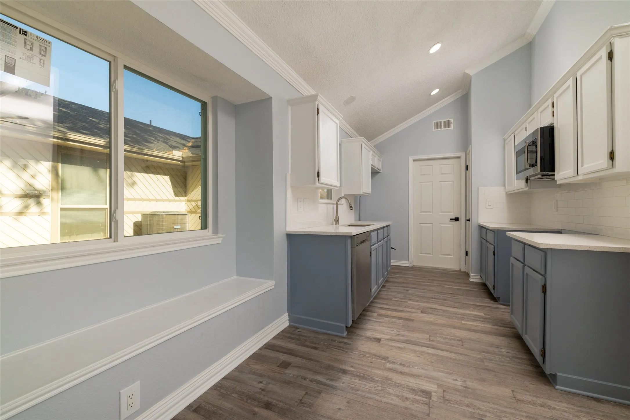 Kitchen featuring wood-like LVP  flooring, two-tone cabinetry, stainless steel appliances, and a vaulted ceiling with recessed lighting
