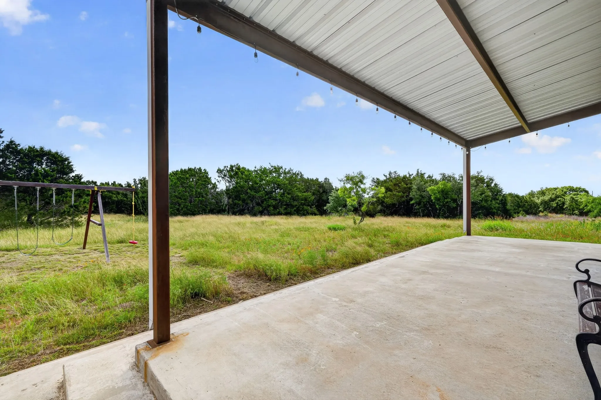 Covered concrete patio with metal roof and string lighting