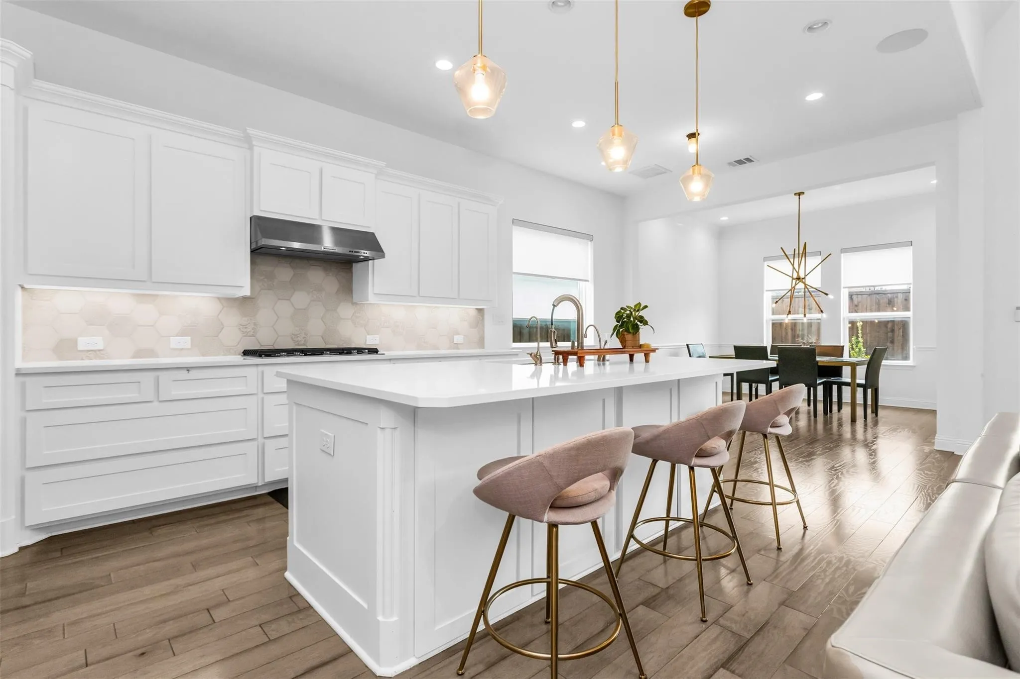Kitchen featuring white cabinetry, a large center island, stainless steel range hood, hexagon tile backsplash, and wood-finish flooring