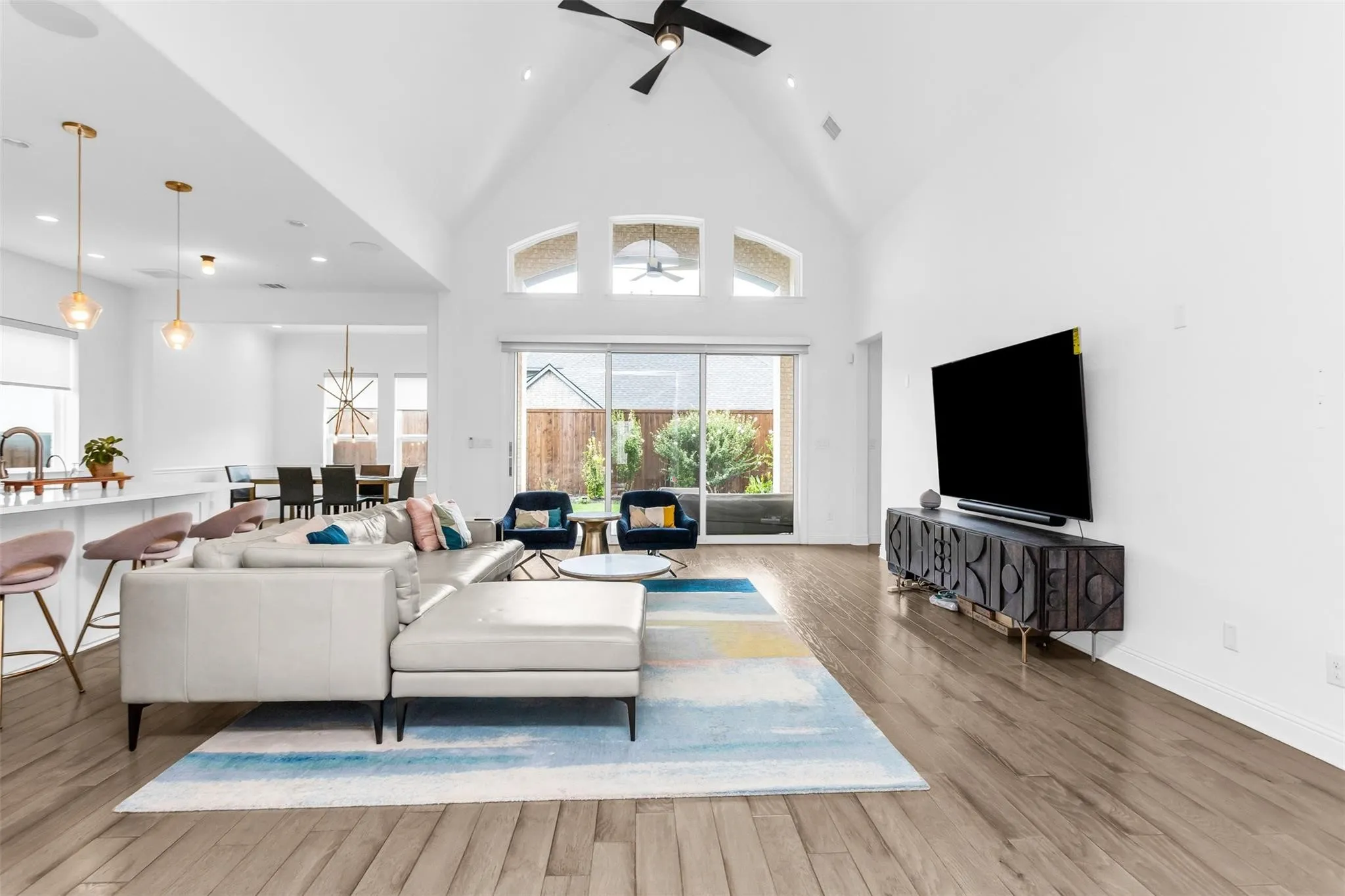 Vaulted ceiling, wood-finish flooring, recessed lighting, large sliding glass door, and a built-in kitchen island with pendant lighting