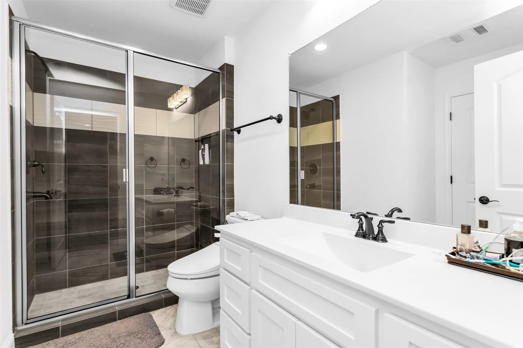 Glass-enclosed shower with dark tile surround and integrated lighting