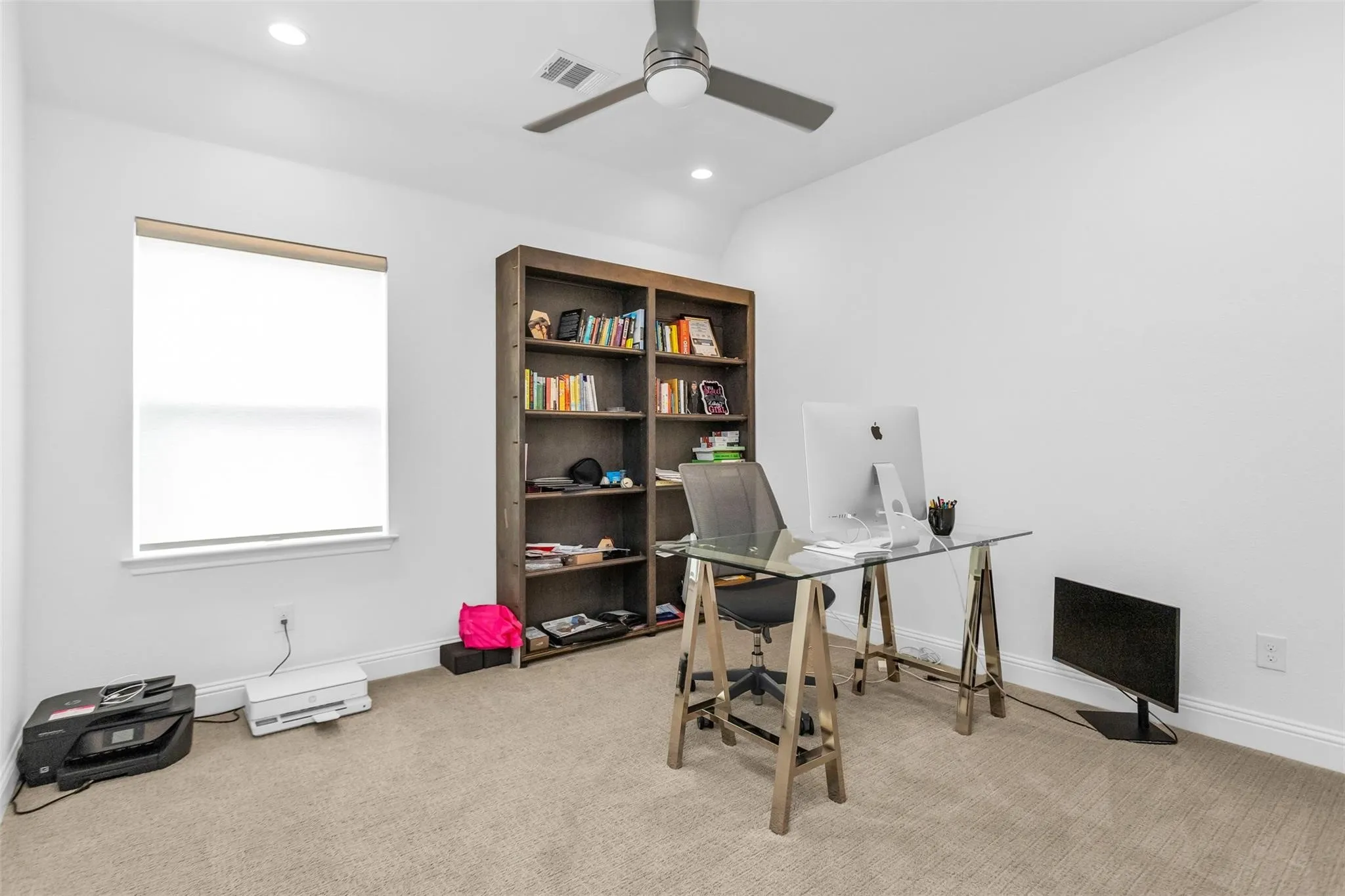 Recessed lighting, ceiling fan, built-in shelving, window with roller shade, and neutral-toned carpeting