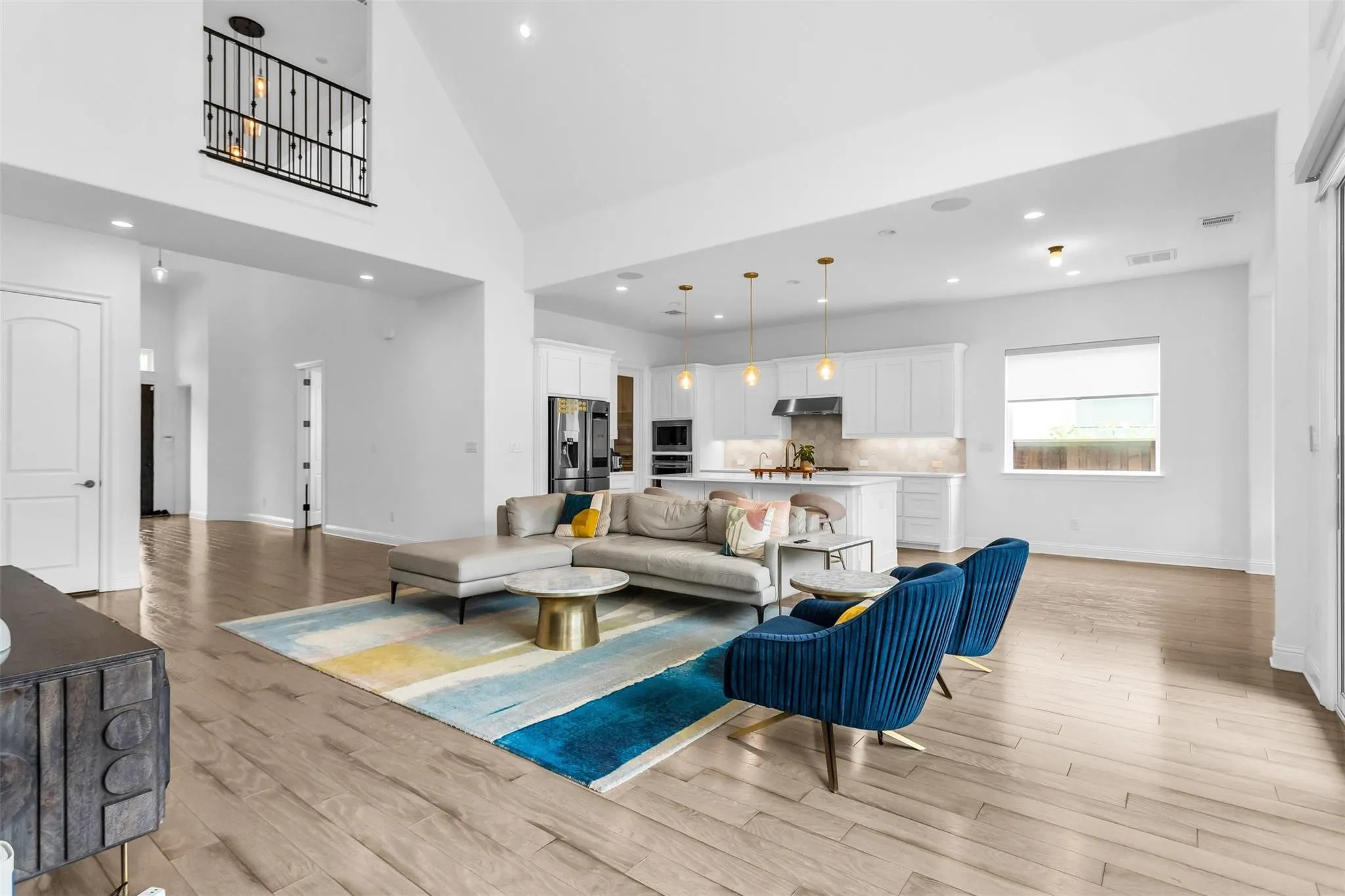 Vaulted ceilings with recessed lighting, open-concept design, wood-finish flooring, kitchen island with pendant lighting, and stainless steel appliances