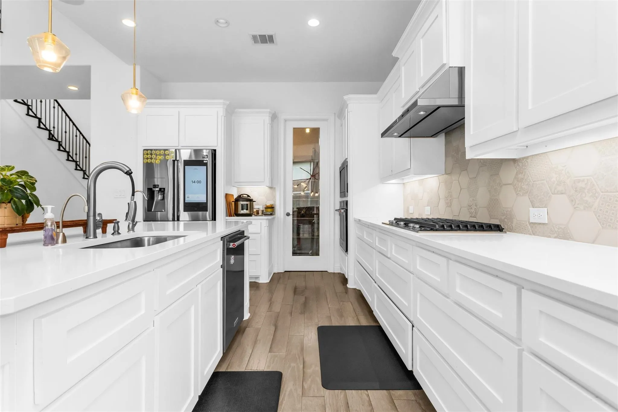 White cabinetry and countertops with a stainless steel sink, gas cooktop, and built-in oven
