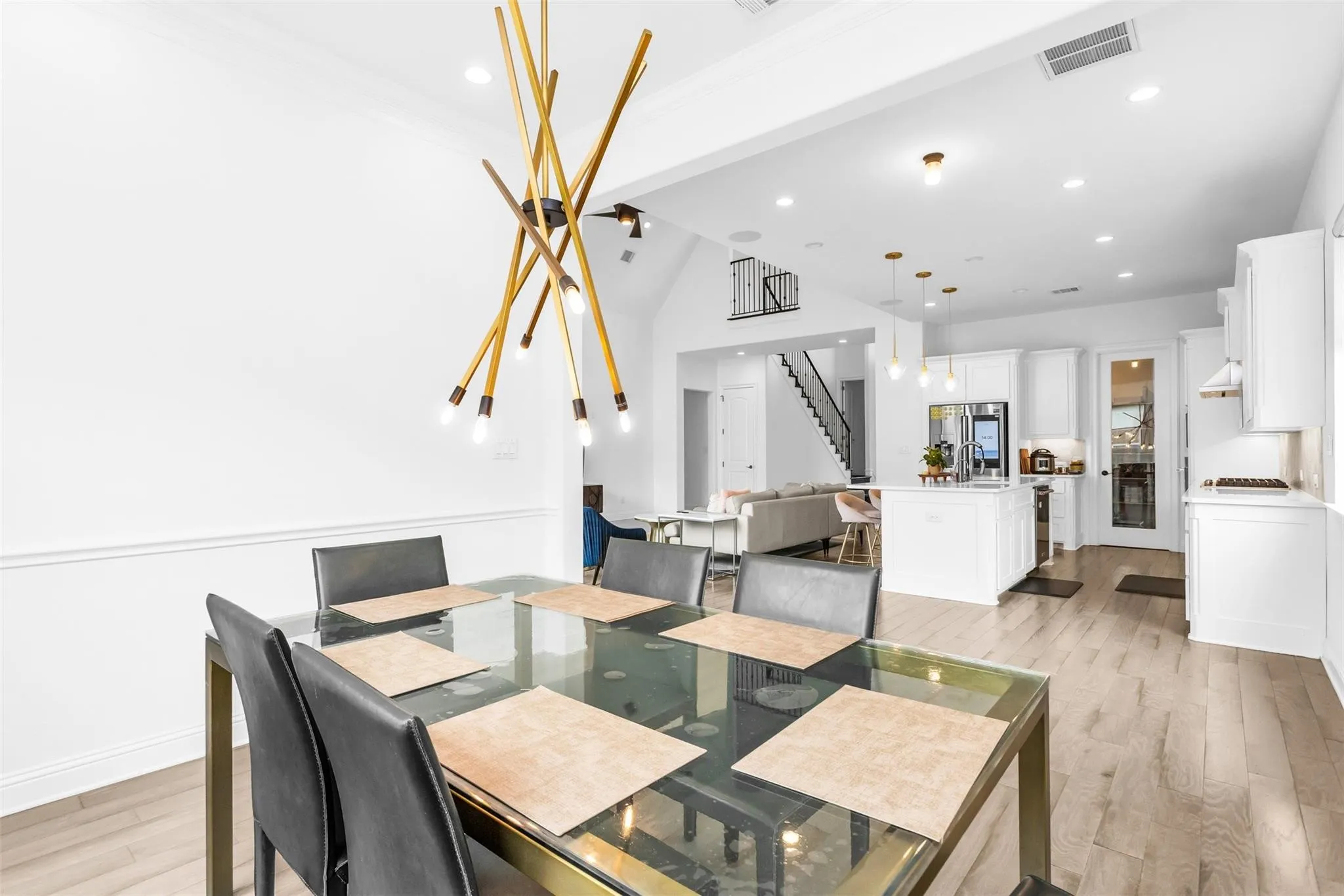 Open-concept main living area with wood-finish flooring, recessed lighting, and a modern chandelier