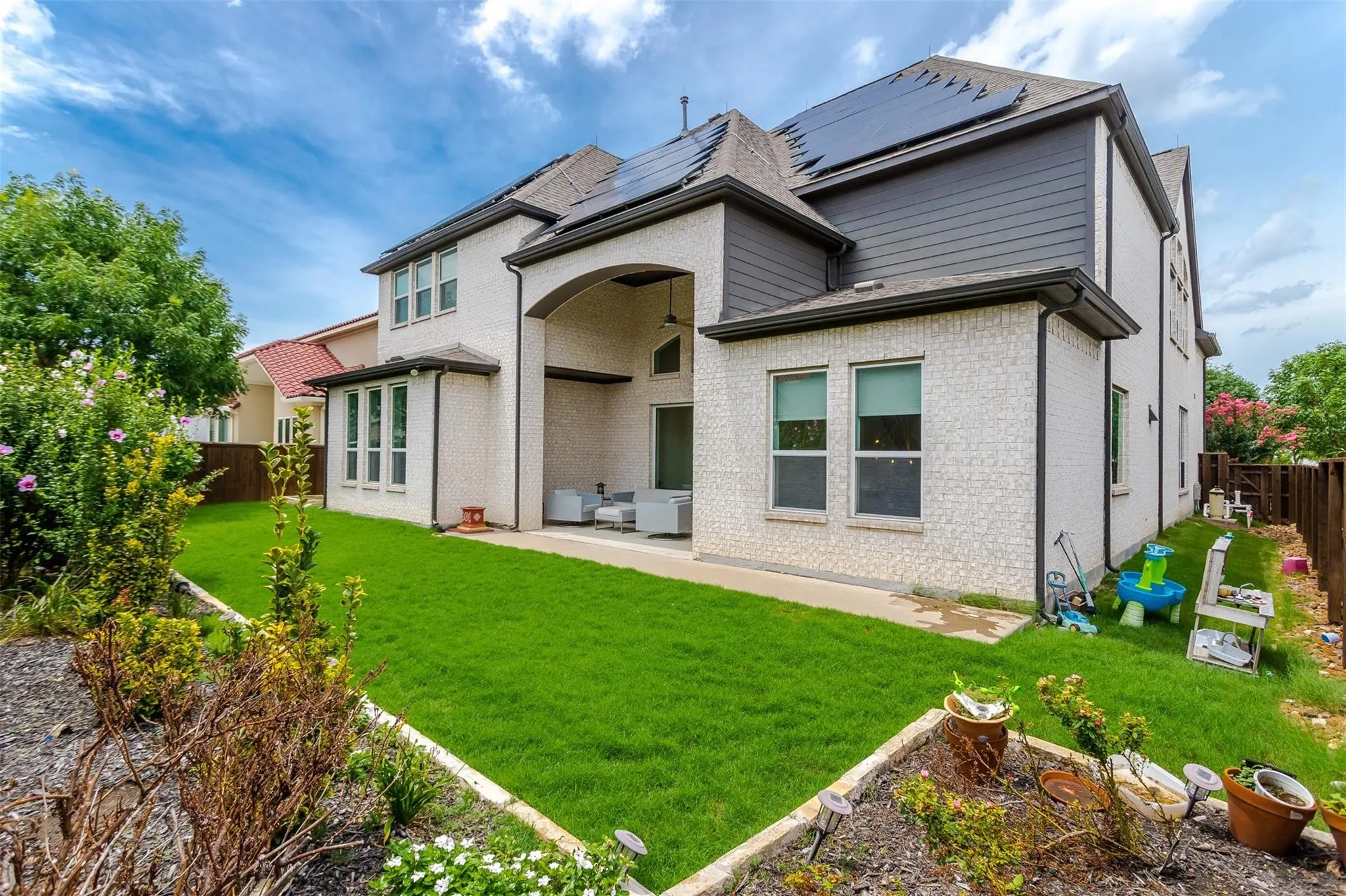 Expansive backyard with a manicured lawn, an extended patio, and raised garden beds