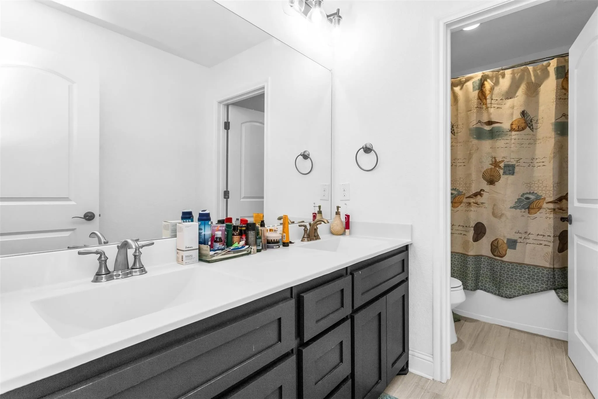 Dual vanity with sleek dark cabinetry, white countertop, and integrated sinks