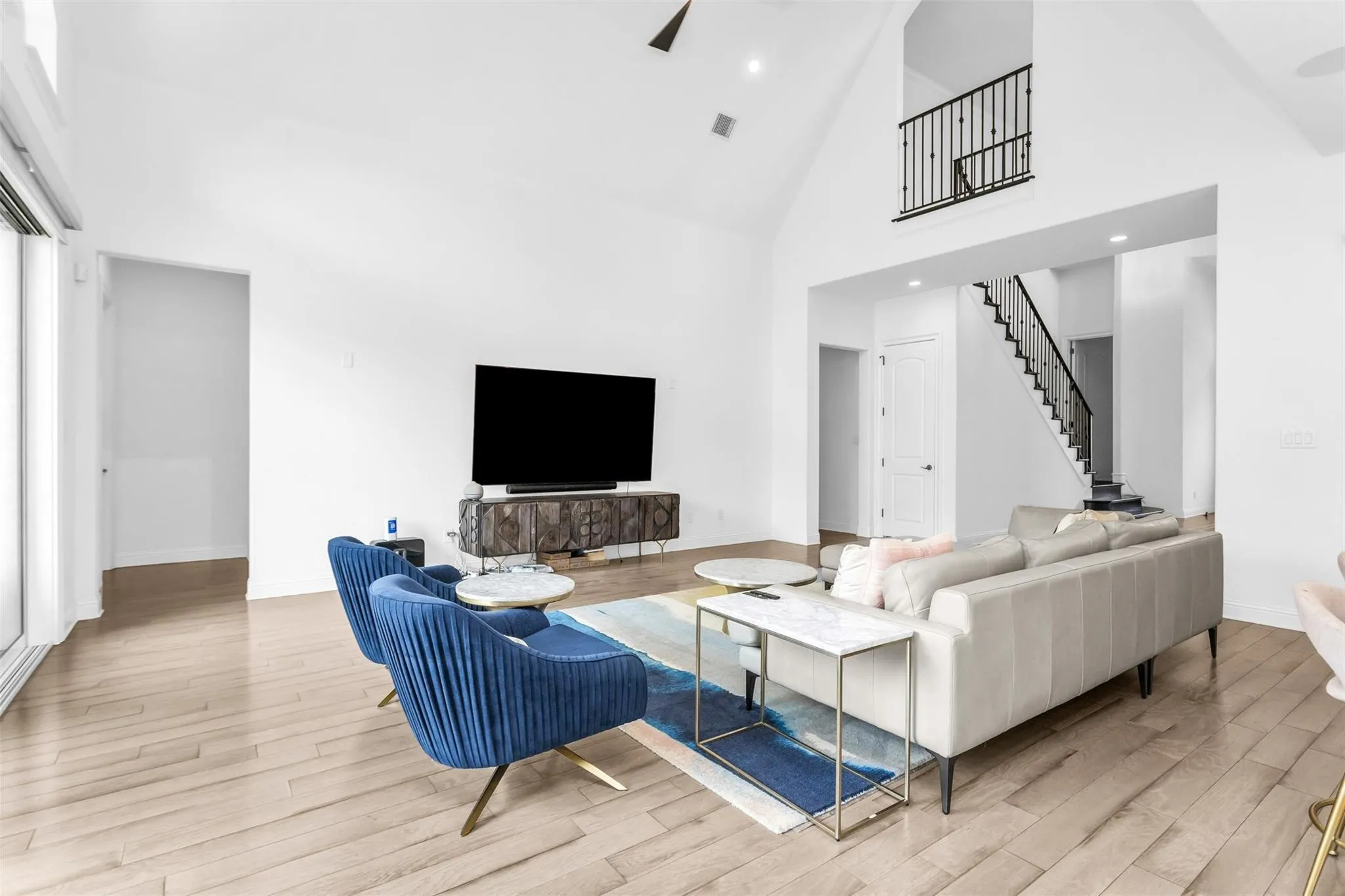 Vaulted ceilings, wood-finish flooring, recessed lighting, and a staircase with wrought iron balusters