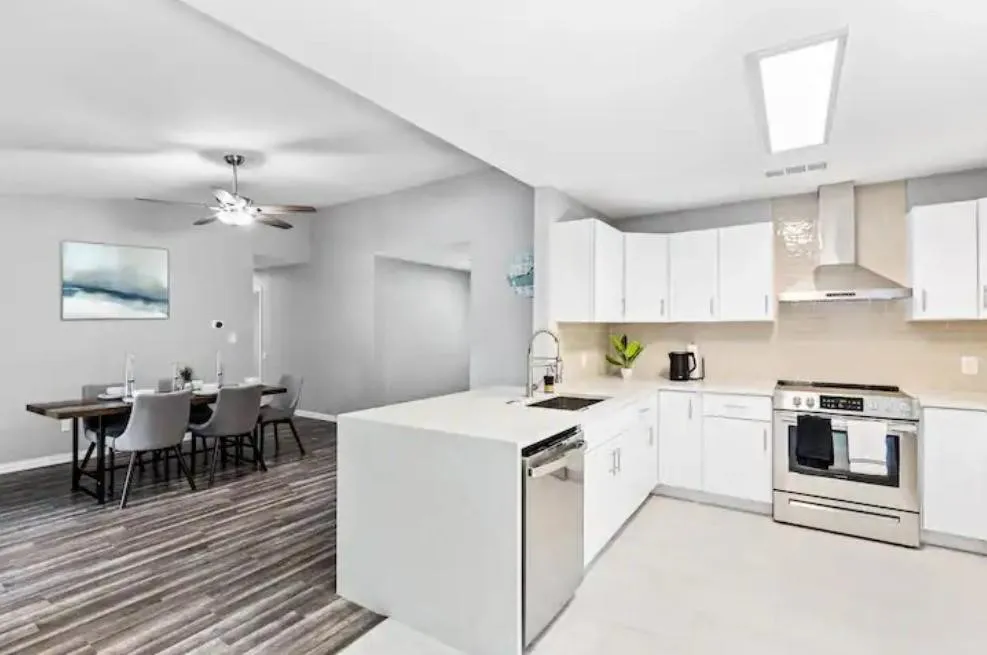 Kitchen featuring white cabinetry, stainless steel appliances, a center island with sink, and a skylight
