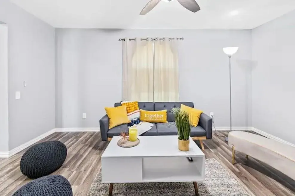 Light gray walls, window with sheer curtains, and a ceiling fan with integrated lighting