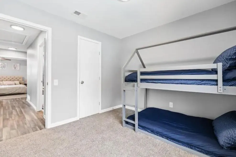 Light gray wall paint with white trim, built-in recessed lighting, carpet flooring, and a white interior door with a brushed nickel doorknob