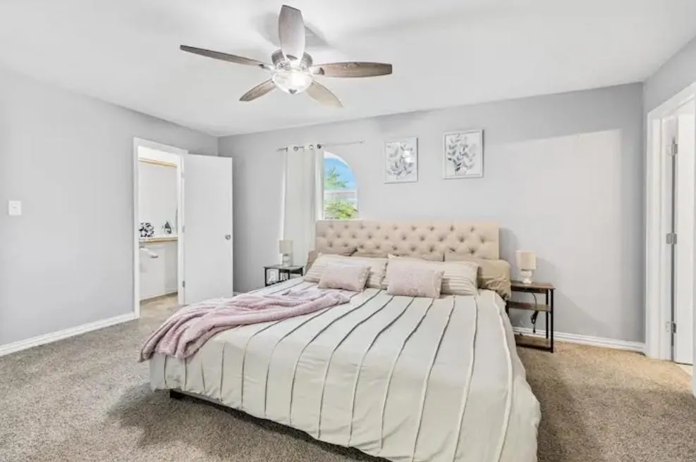 Carpet flooring, ceiling fan with integrated lighting, arched window, and an en-suite bathroom