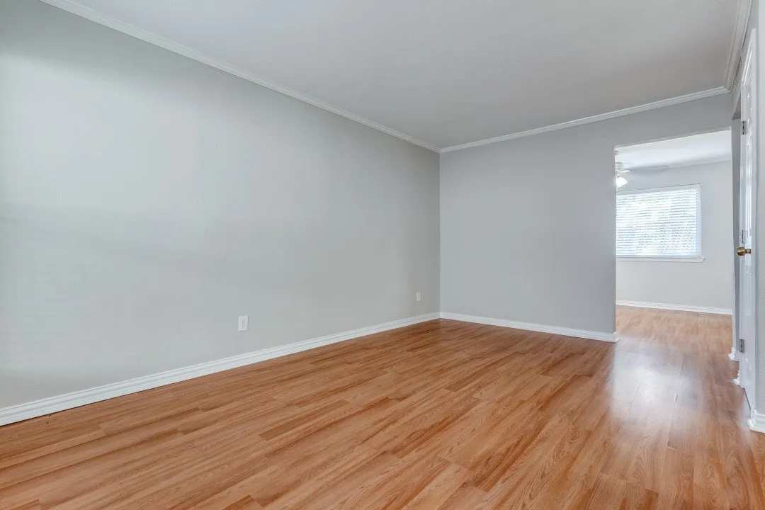 Wood-finish flooring throughout, light gray wall finishes, and white crown molding