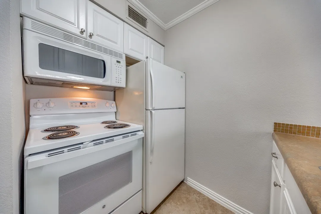 White cabinetry with silver-tone hardware, white oven with built-in microwave, white refrigerator, and tile flooring