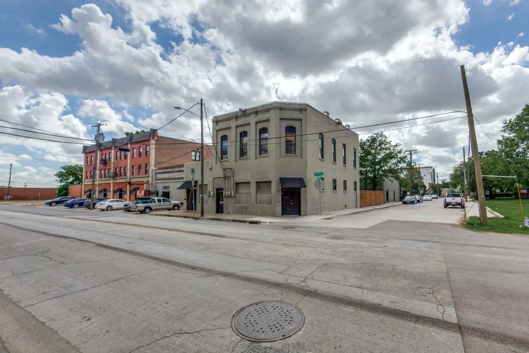 Corner commercial building with multiple windows, black awnings, and an adjacent parking area