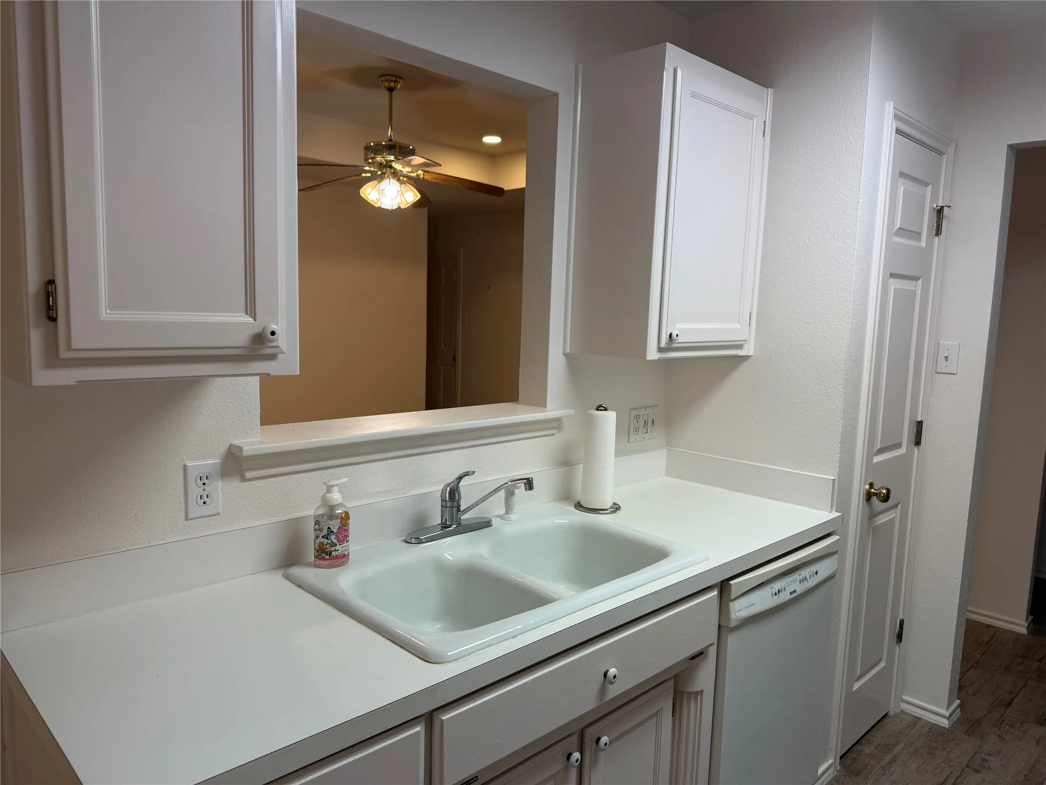 White cabinetry with traditional paneling, a double basin sink, and a built-in dishwasher