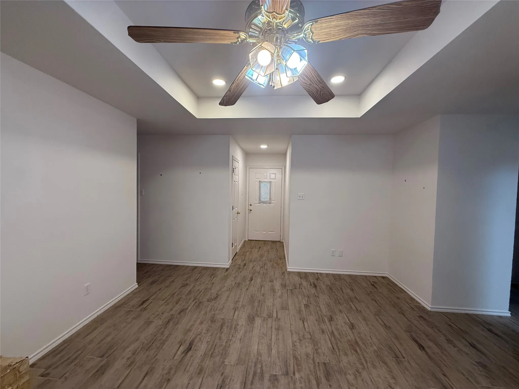Recessed lighting, wood-finish flooring, central ceiling fan, tray ceiling, and white interior doors