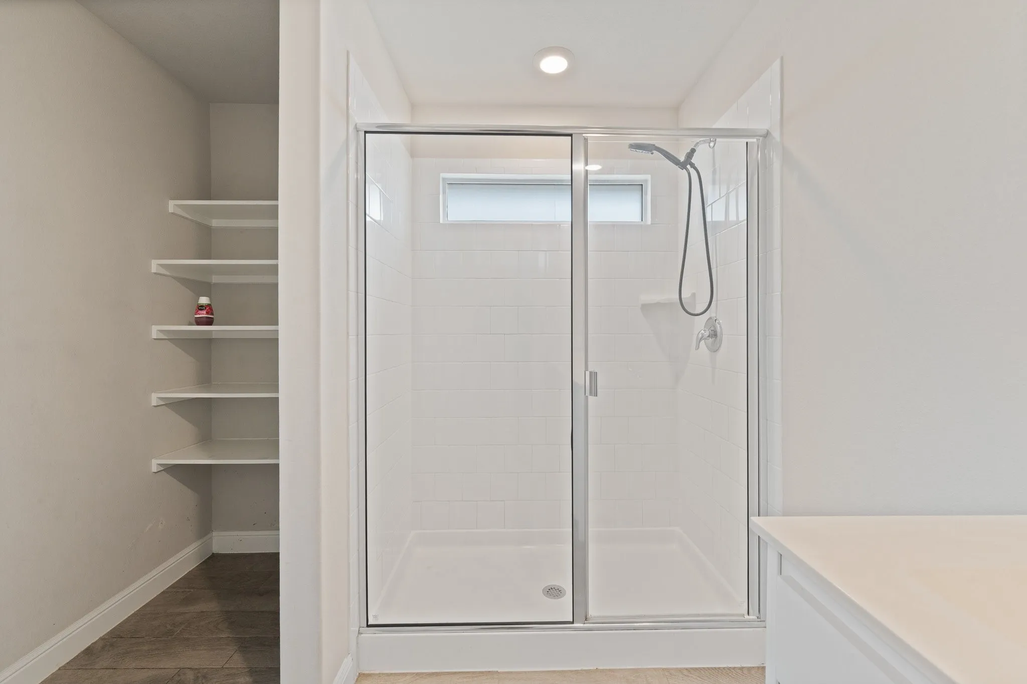 Enclosed shower with glass sliding doors, recessed lighting, and a transom window