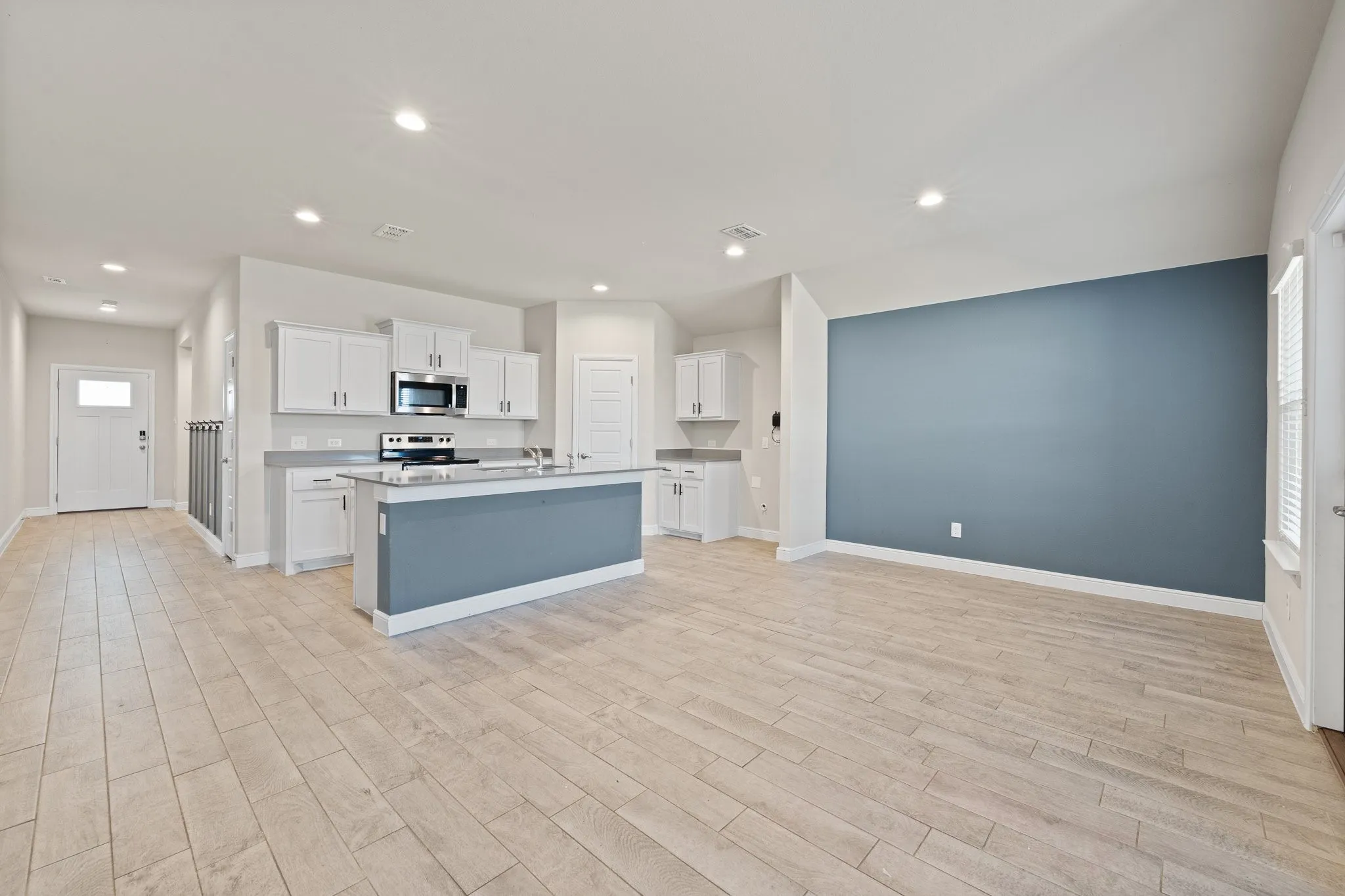 Open-concept layout featuring wood-finish flooring, recessed lighting, and a kitchen island with seating