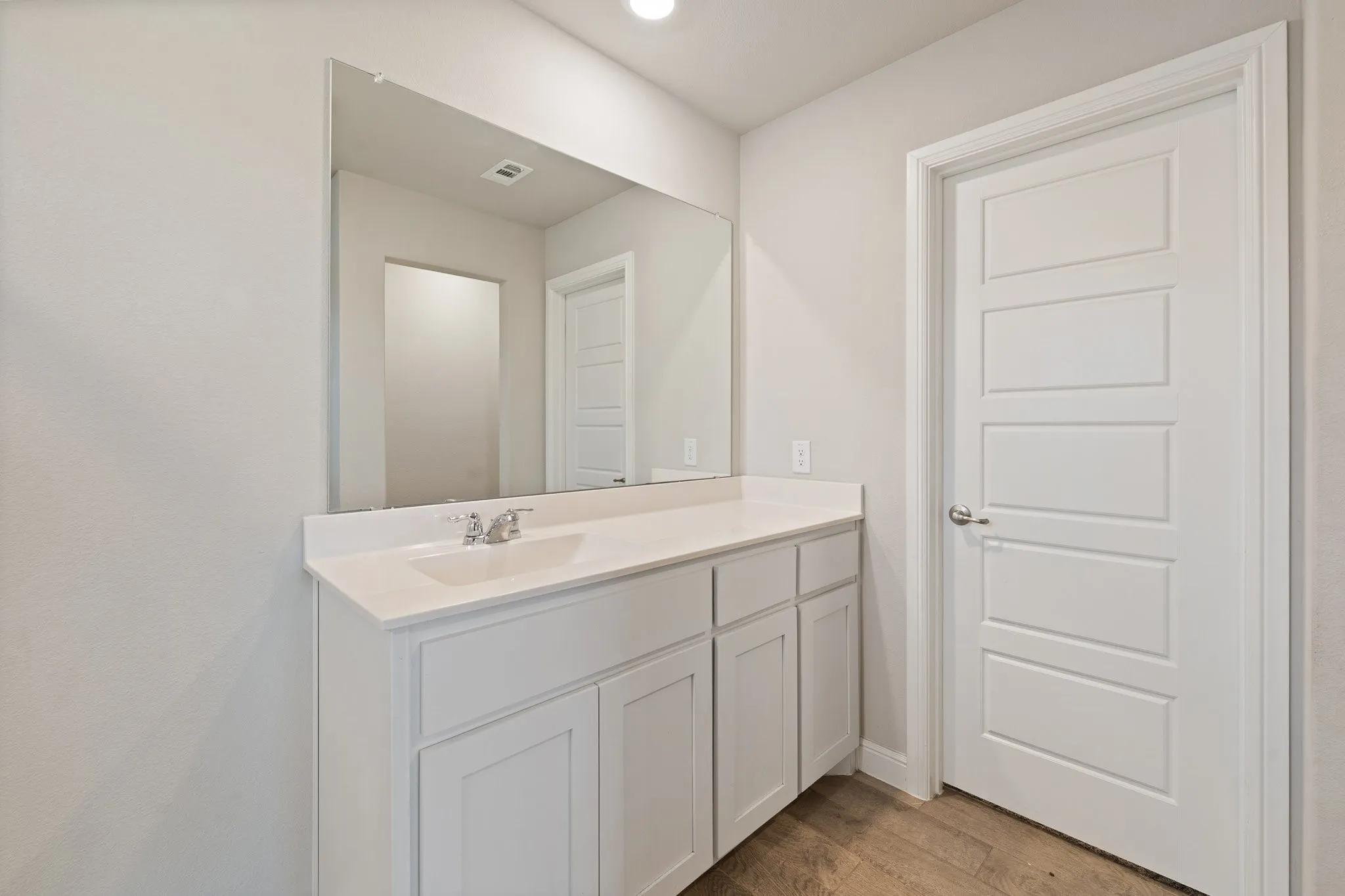 Built-in vanity with white cabinetry, integrated sink, and chrome faucet