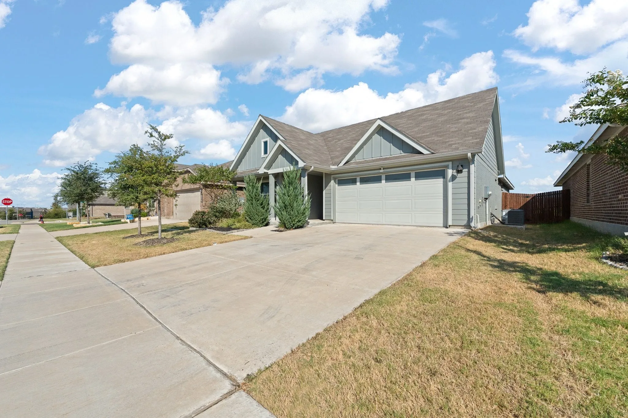Front exterior featuring a two-car garage, concrete driveway, and a partially fenced side yard