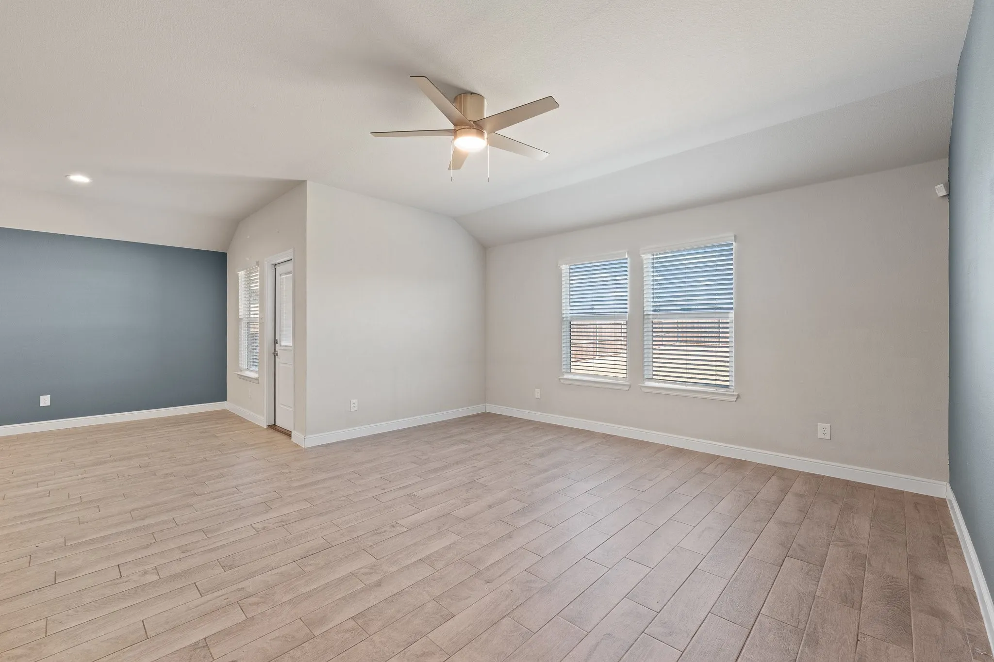 Expansive room featuring wood-finish tile flooring, recessed lighting, and a ceiling fan
