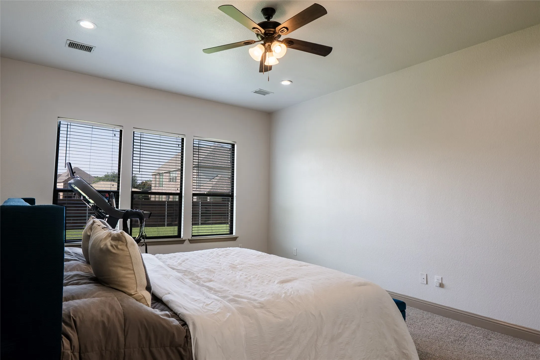 Triple windows with blinds, ceiling fan with integrated lighting, recessed lighting, and carpeted flooring