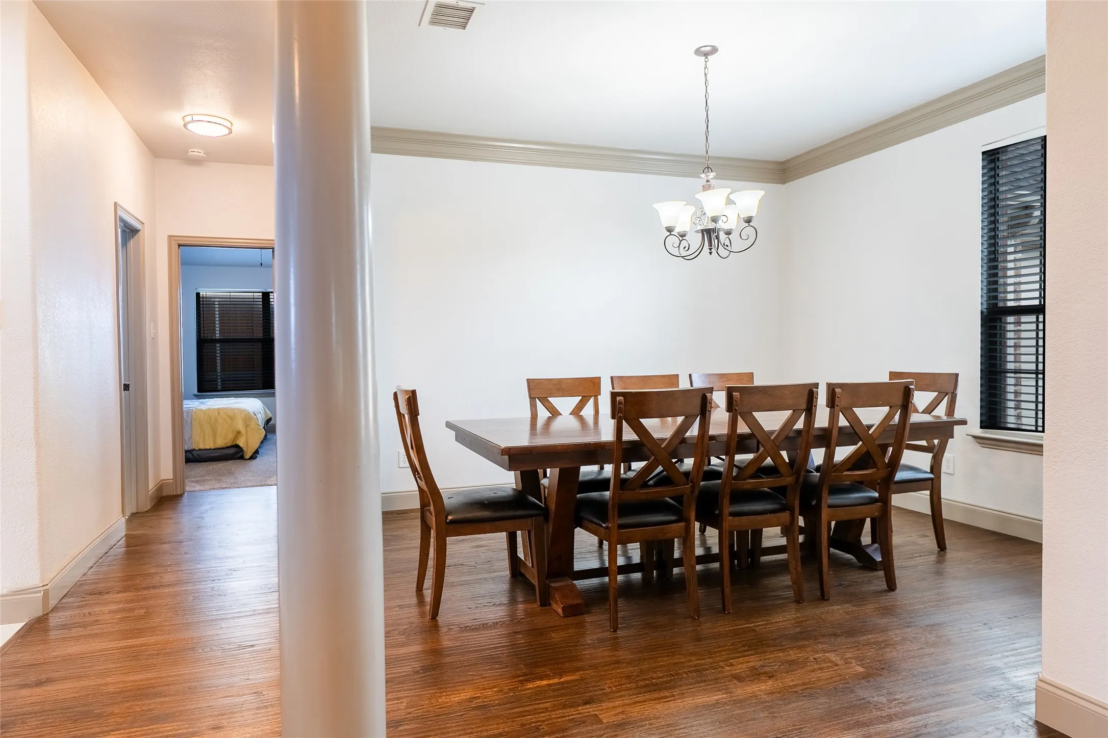 Recessed lighting, wood-finish flooring, white walls, crown molding, and a traditional chandelier