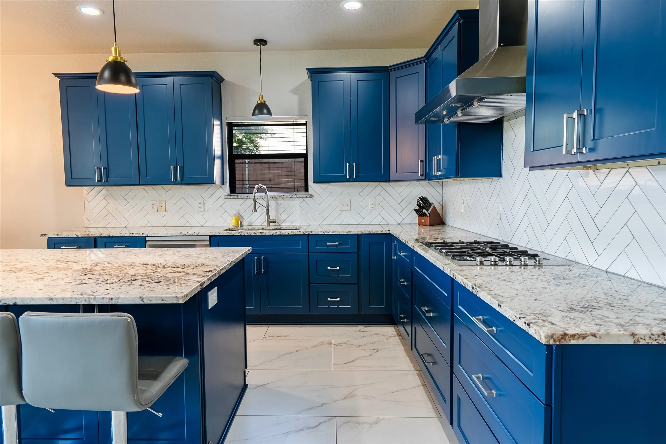 Kitchen featuring blue shaker cabinetry, light-toned countertops, a herringbone tile backsplash, a gas range, and a kitchen island