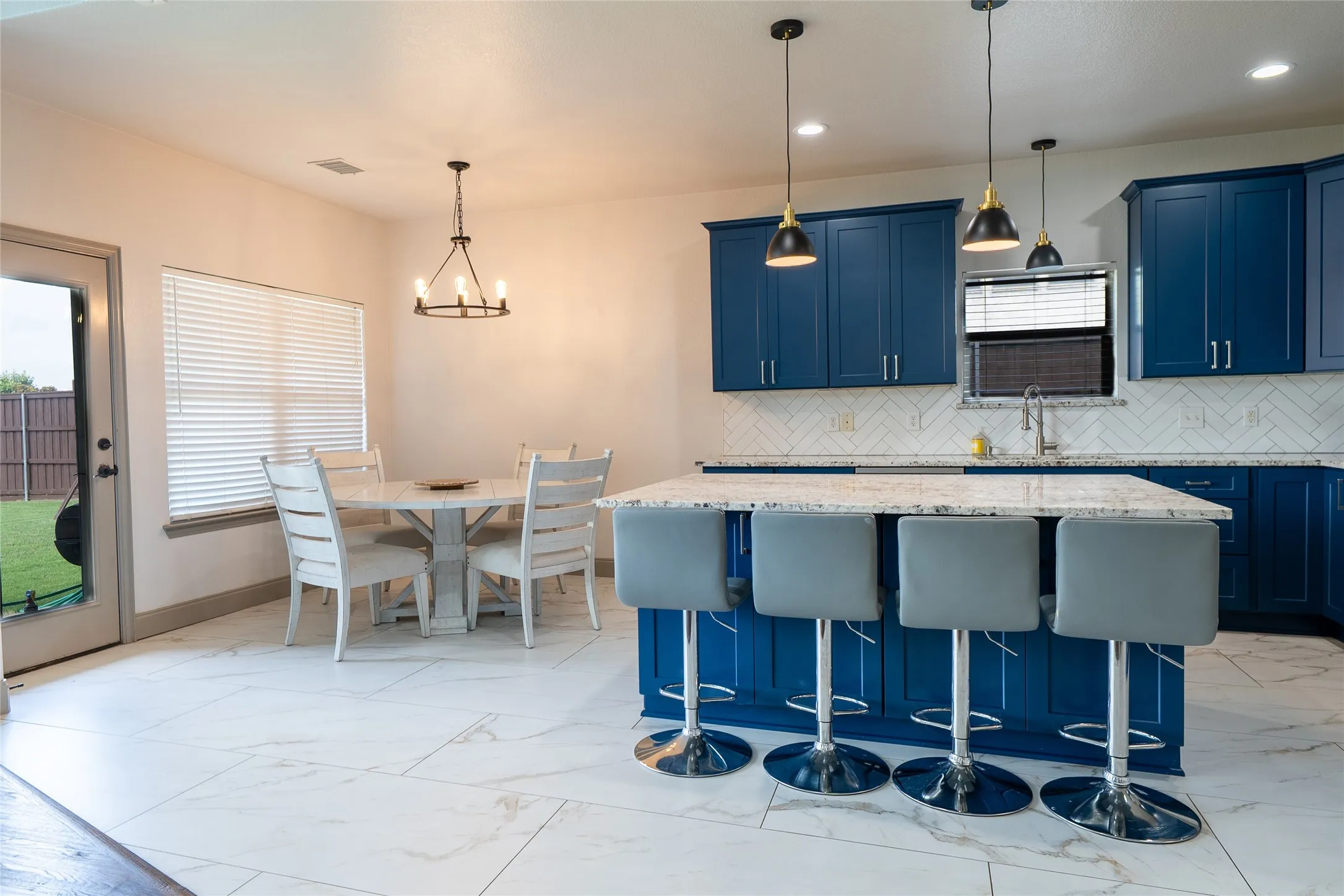 Modern kitchen featuring custom blue cabinetry with stainless steel hardware, quartz countertops, and a large waterfall-edge island with seating for four