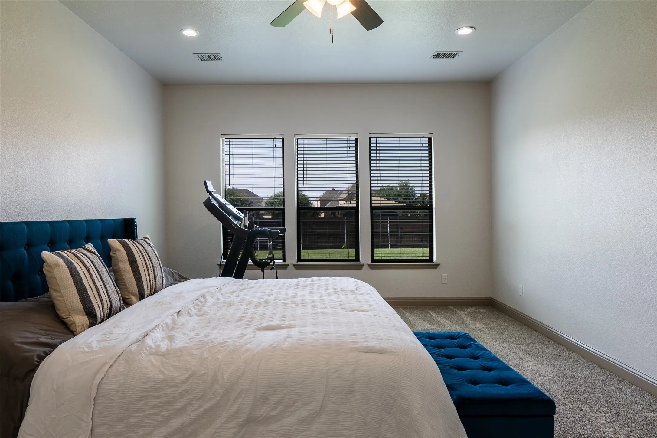 Recessed lighting, ceiling fan, three windows with blinds, and carpeted flooring