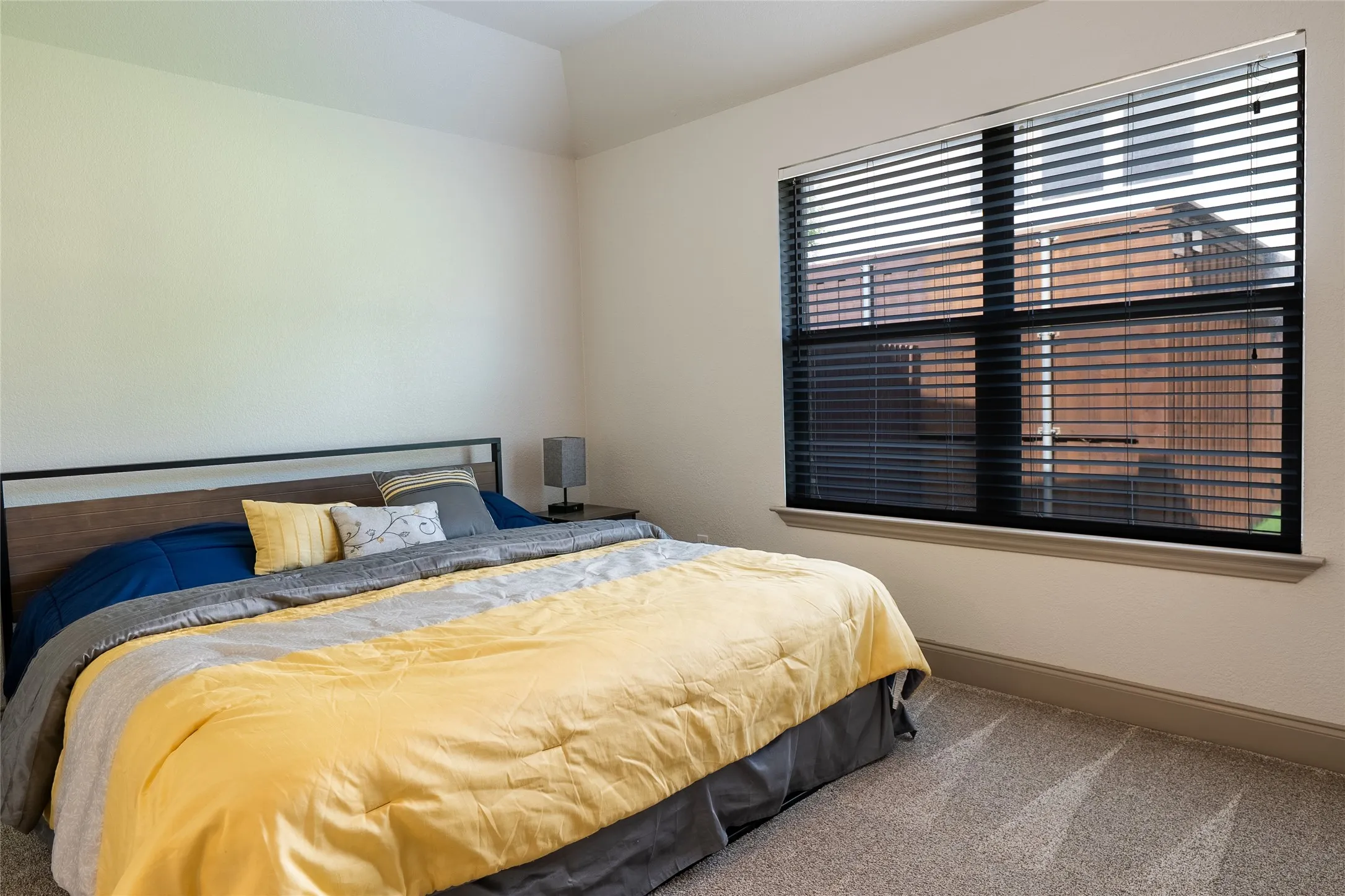 Neutral wall paint, carpet flooring, a large window with horizontal blinds, and crown molding