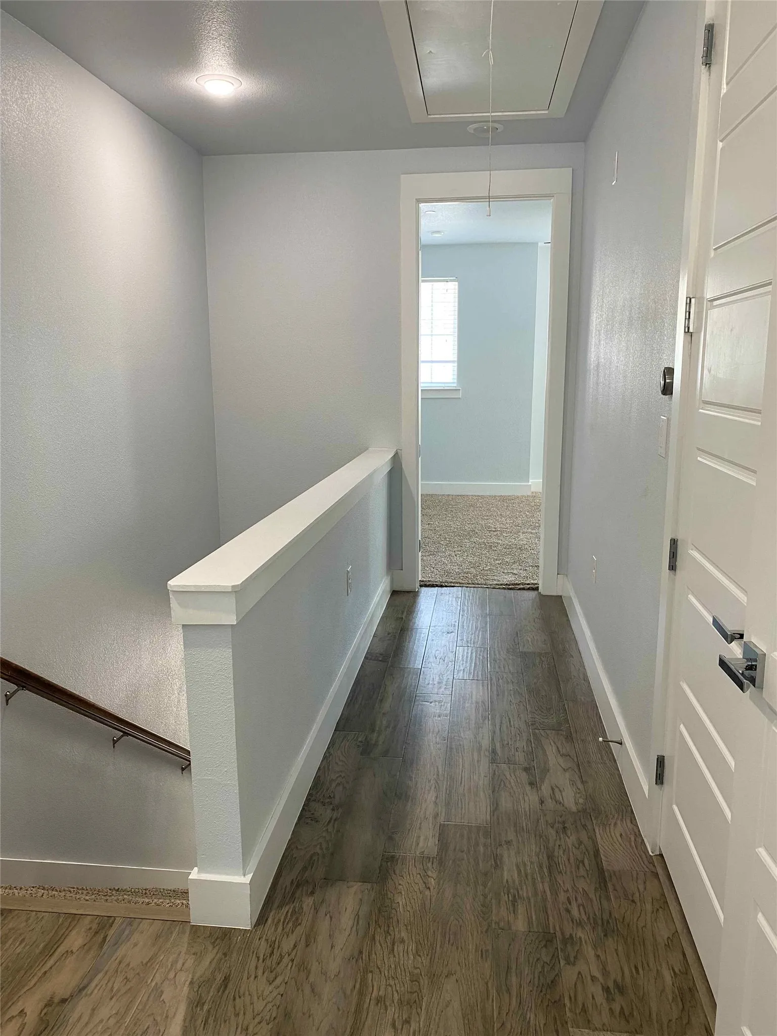 Corridor with dark wood-type flooring and an upstairs landing