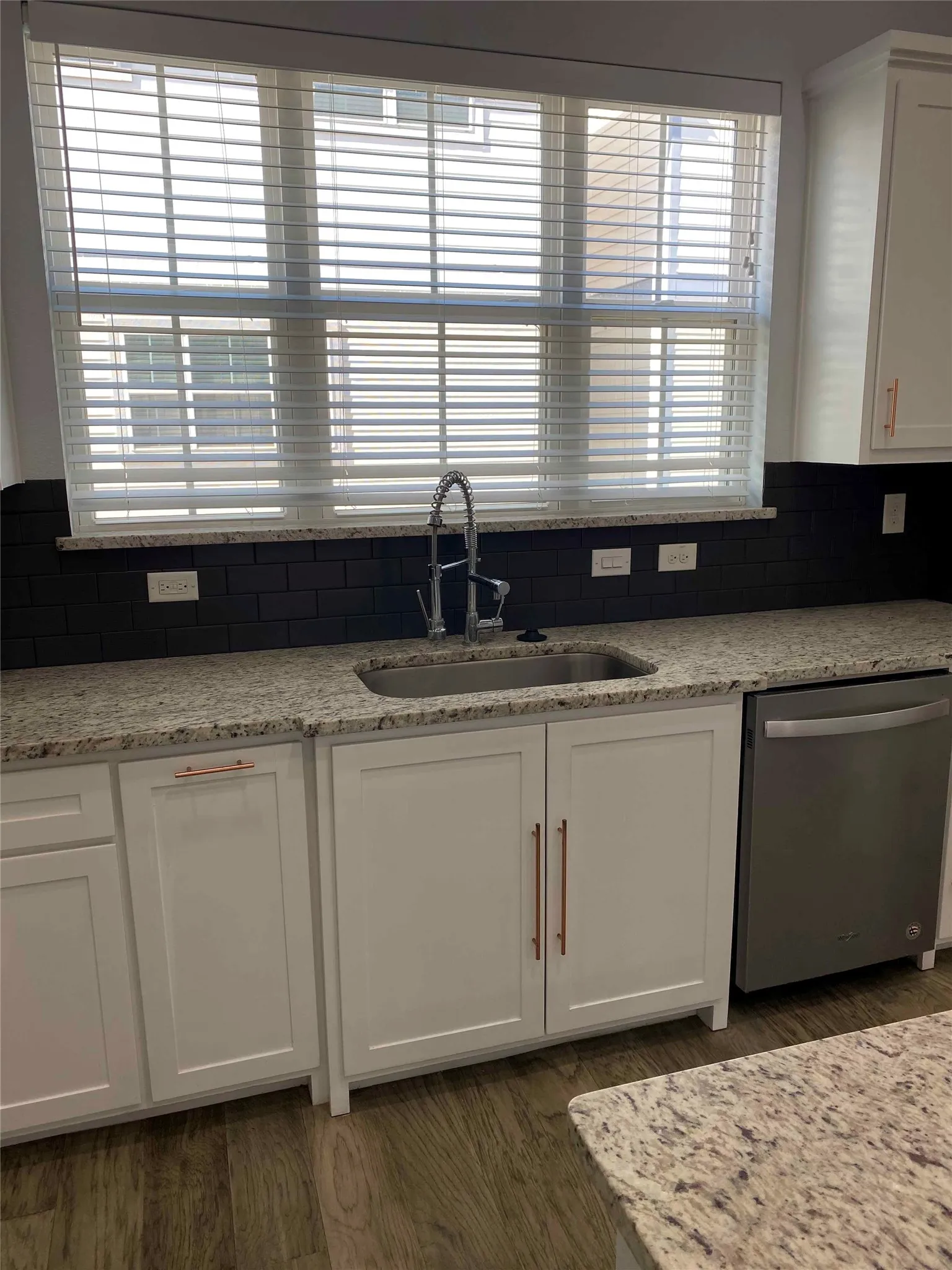 Kitchen featuring white cabinetry, dishwasher, light stone counters, and dark wood finished floors