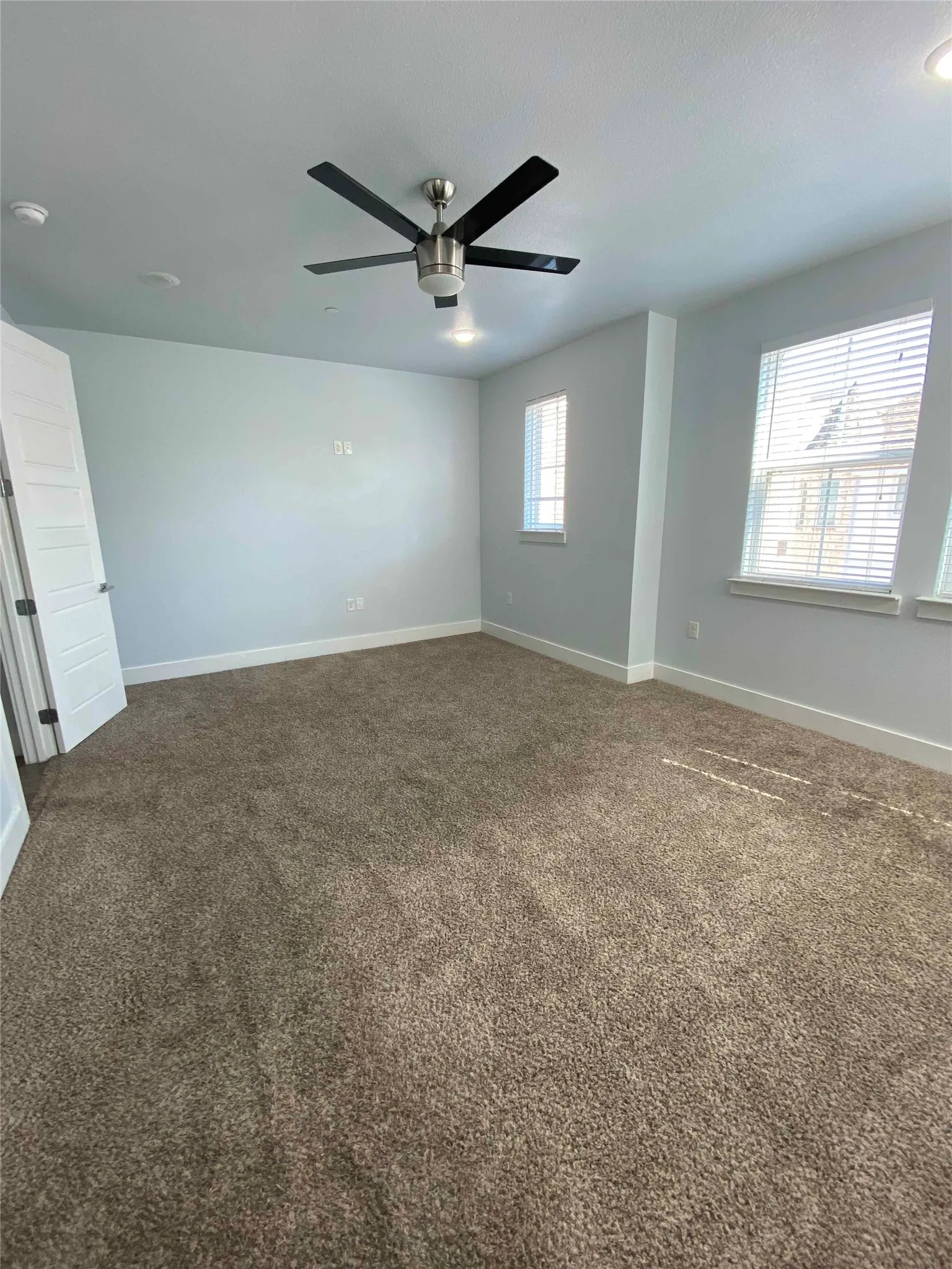 Unfurnished room with dark carpet and ceiling fan