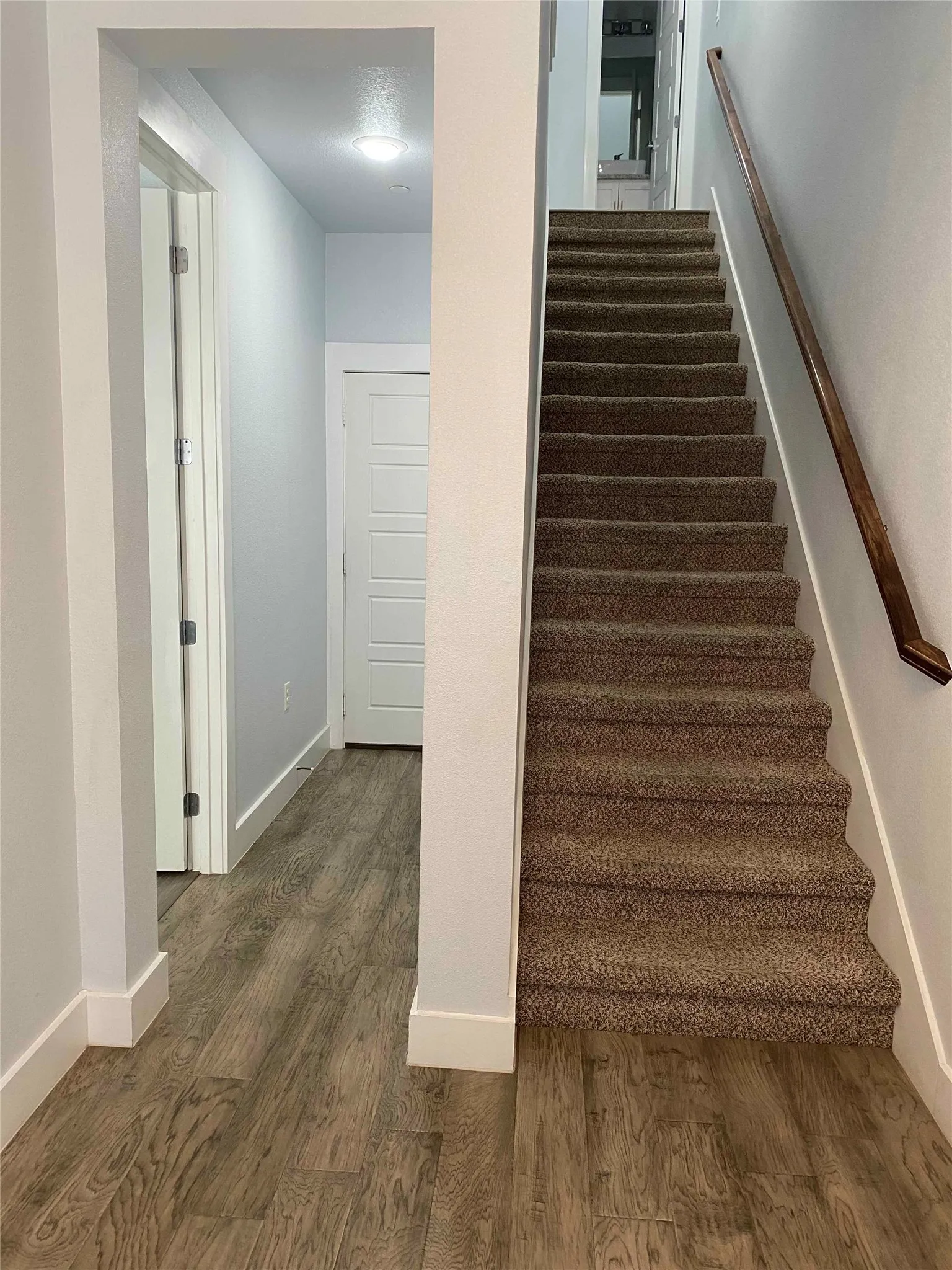 Stairs with wood finished floors and baseboards