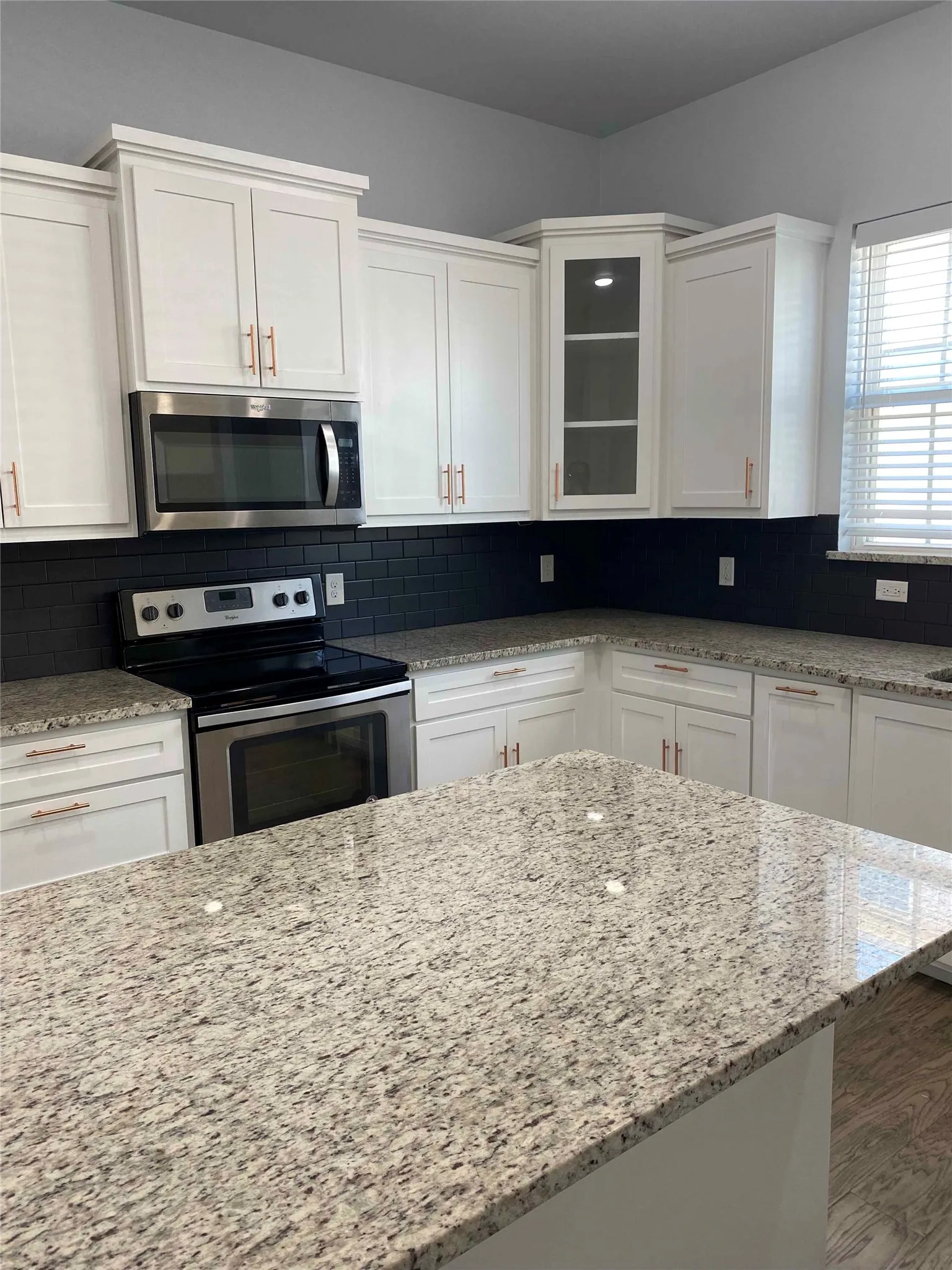 Kitchen featuring white cabinets, stainless steel appliances, and light stone counters