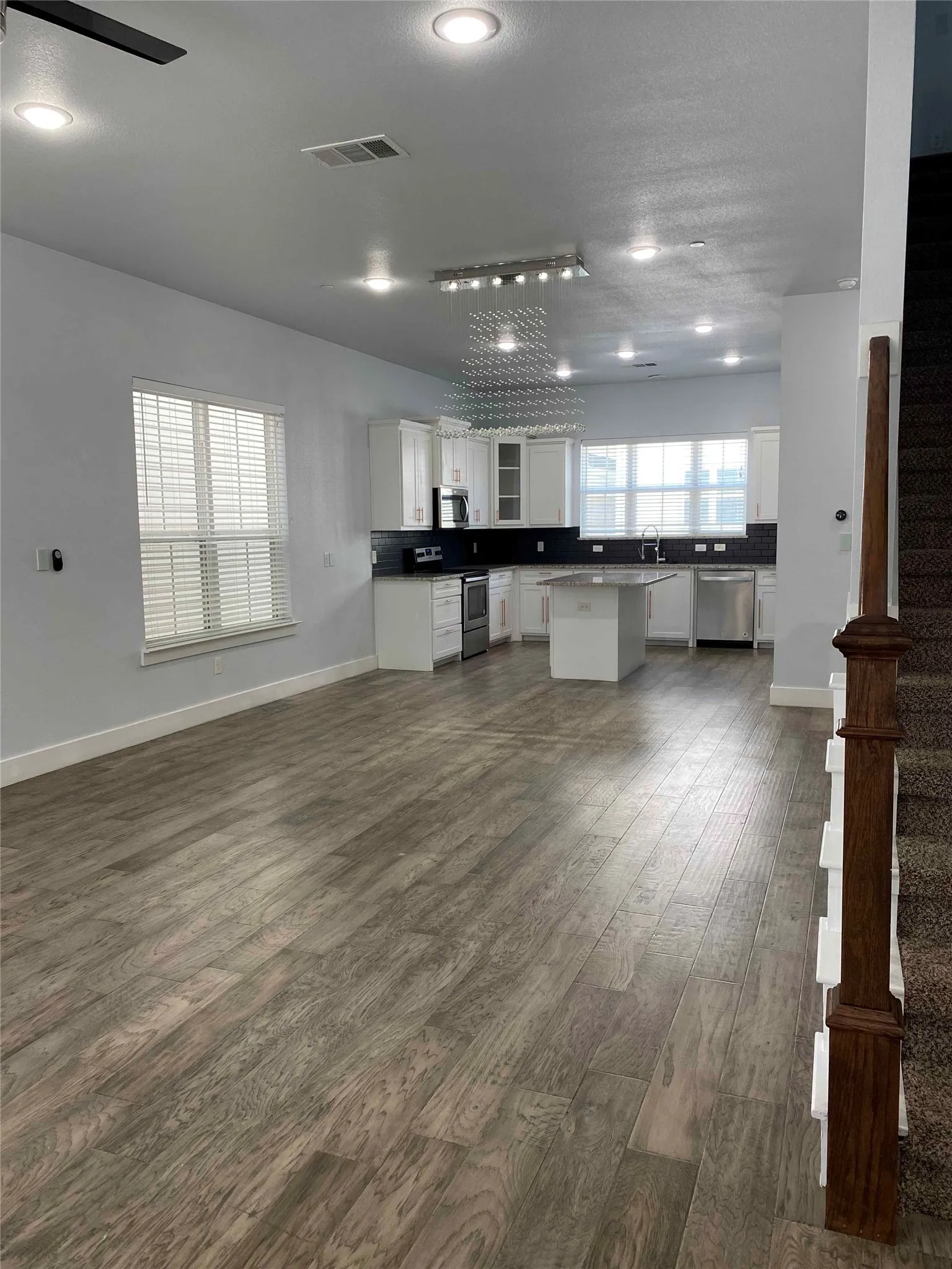 Kitchen featuring white cabinets, dark wood-type flooring, stainless steel appliances, a center island, and open floor plan