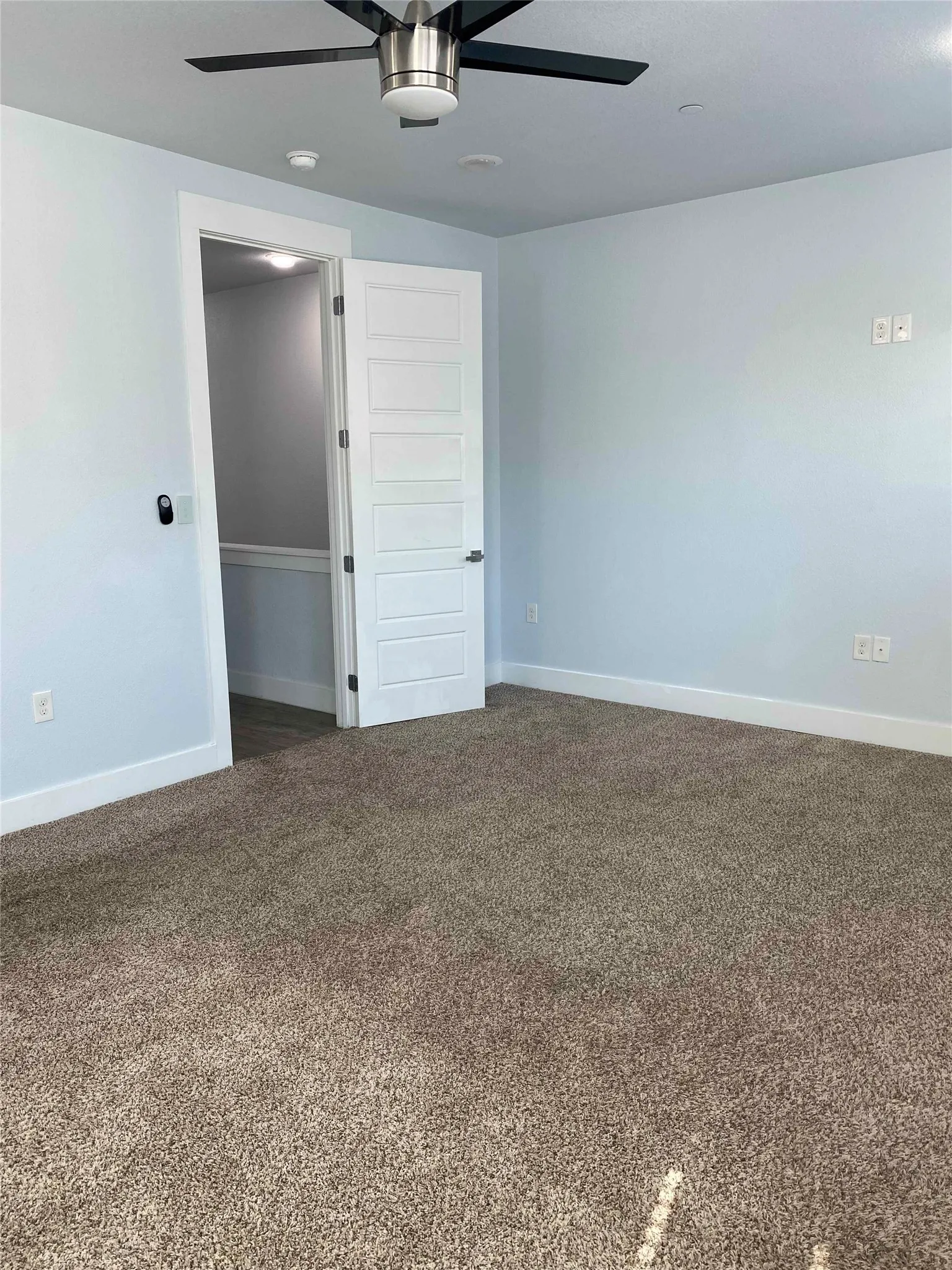 Spare room with a ceiling fan and dark colored carpet
