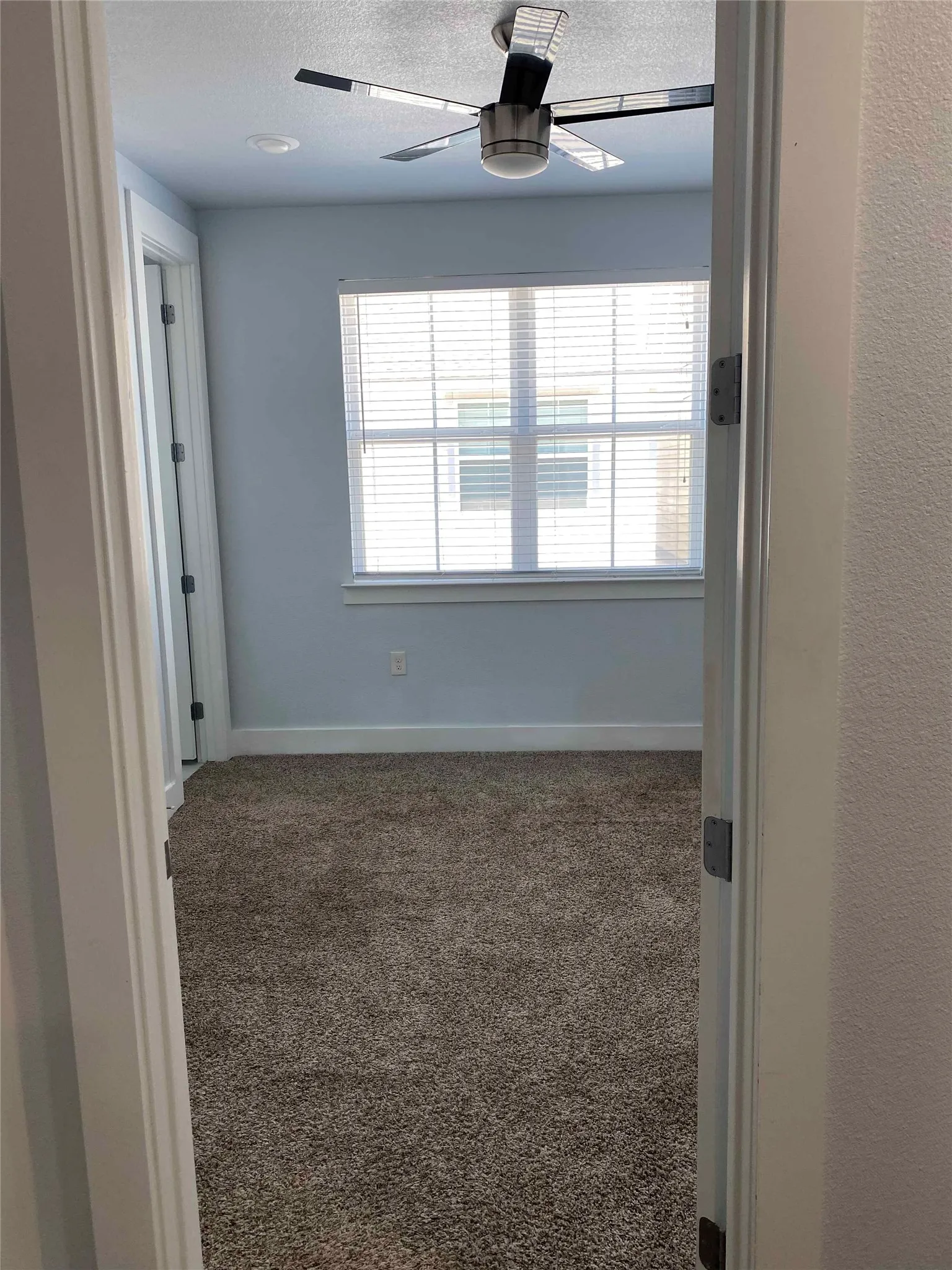 Spare room featuring dark carpet, a ceiling fan, and a textured ceiling