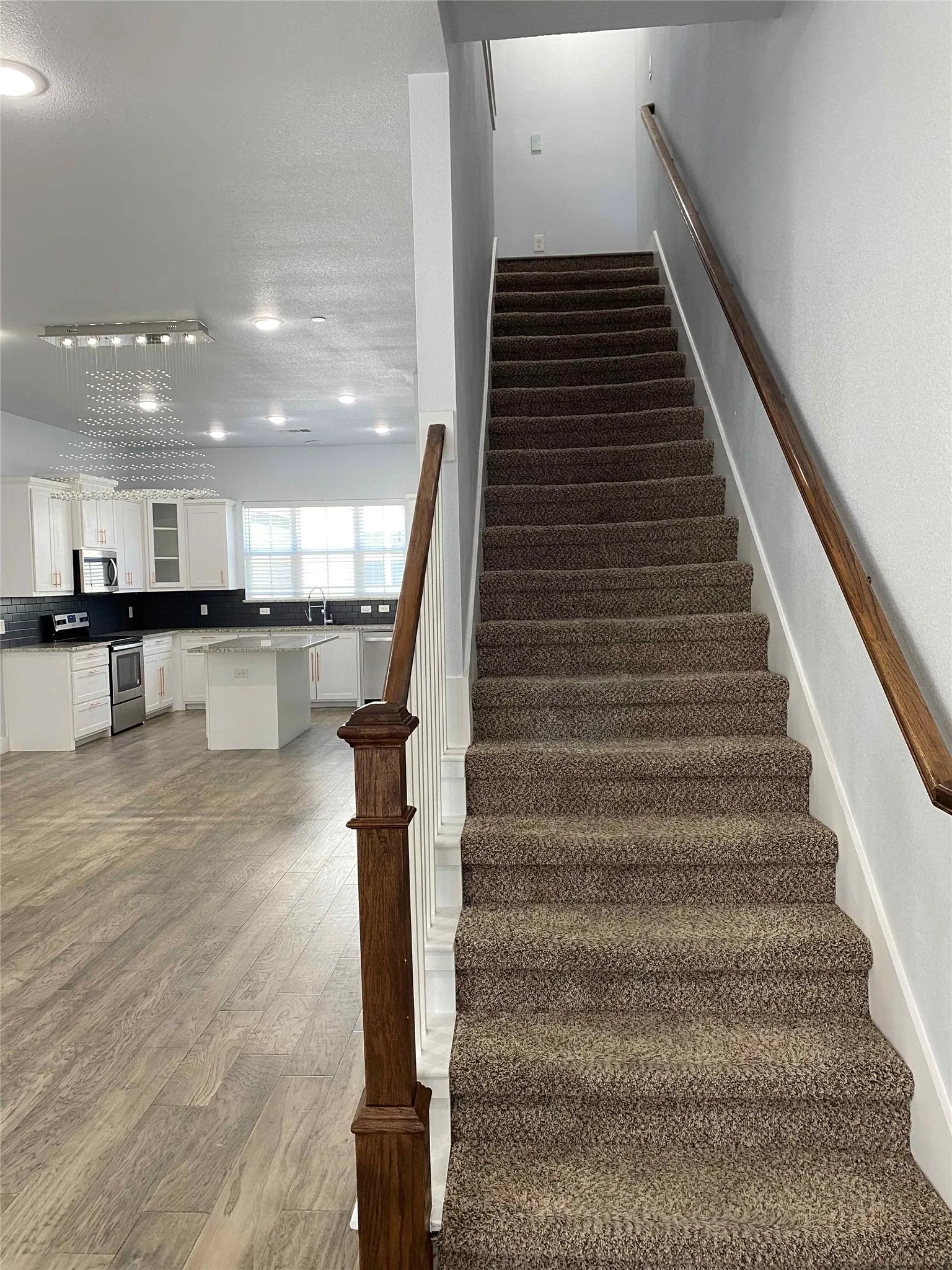 Stairs with wood finished floors and recessed lighting